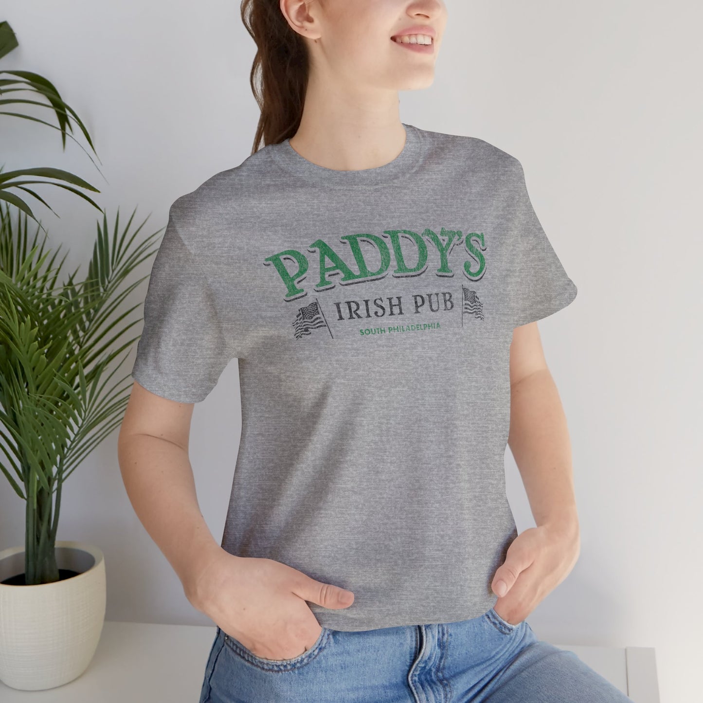 Woman wearing athletic heather gray t-shirt with vintage Paddy's Pub Irish Bar graphic inspired by It’s Always Sunny in Philadelphia.