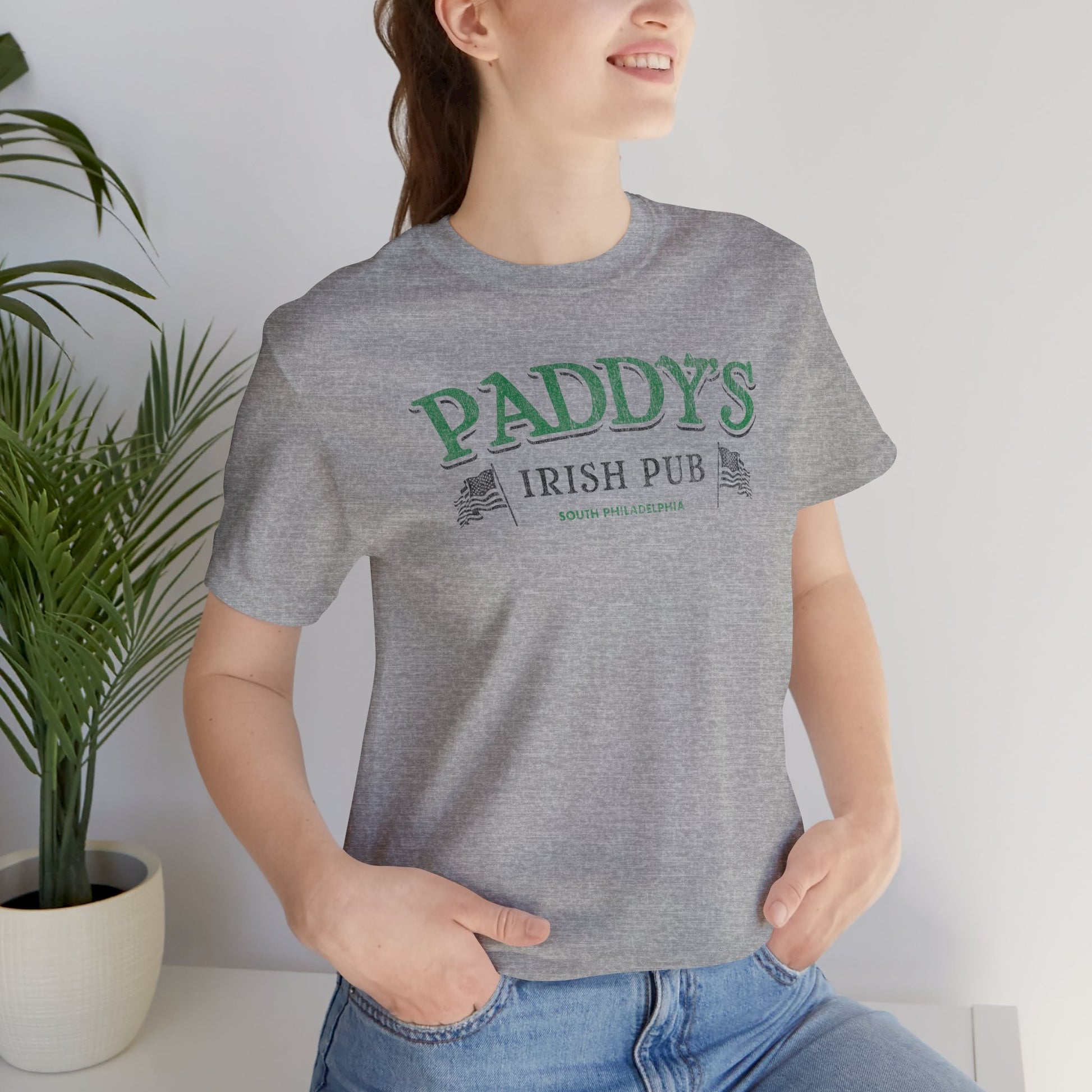 Woman wearing athletic heather gray t-shirt with vintage Paddy's Pub Irish Bar graphic inspired by It’s Always Sunny in Philadelphia.