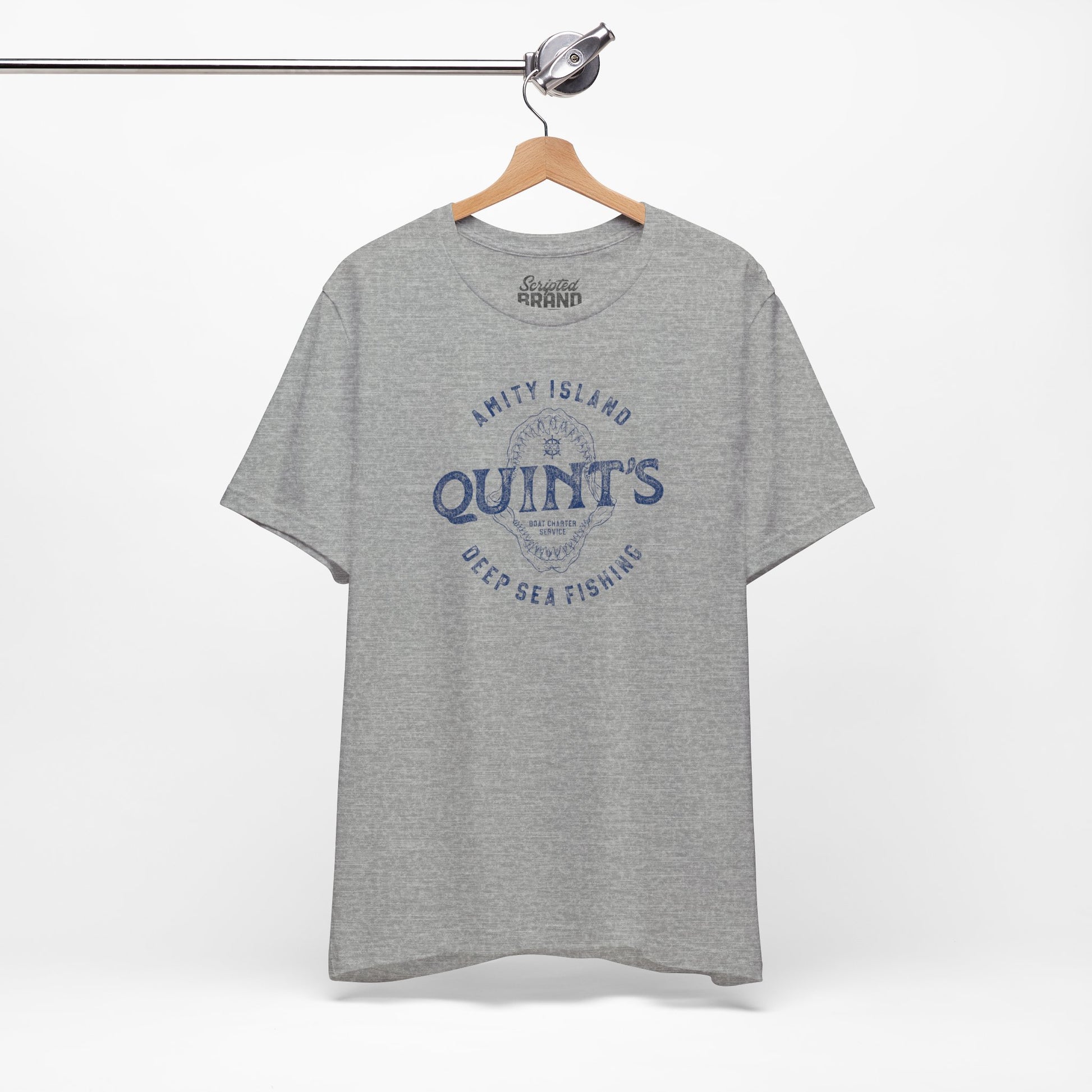 Athletic Heather Gray colored Soft short-sleeve t-shirt on a hanger featuring the Quint's Deep Sea Fishing Boat Charters logo graphic inspired by the movie Jaws in a vintage distressed ink-stamped worn-in style.