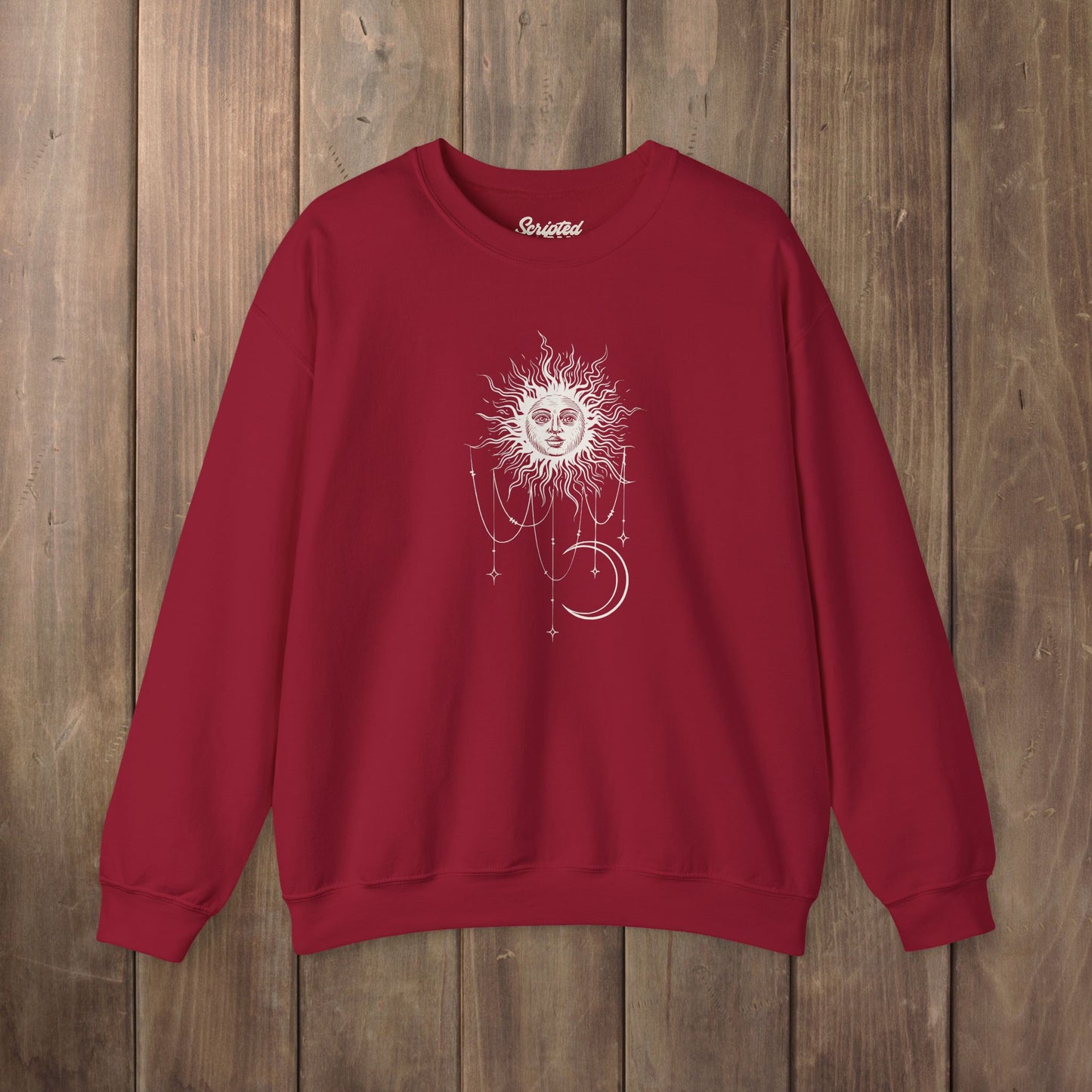 Cardinal red crewneck sweatshirt with boho celestial sun face, stars, and crescent moon design worn by Patricia in Widow's Bay