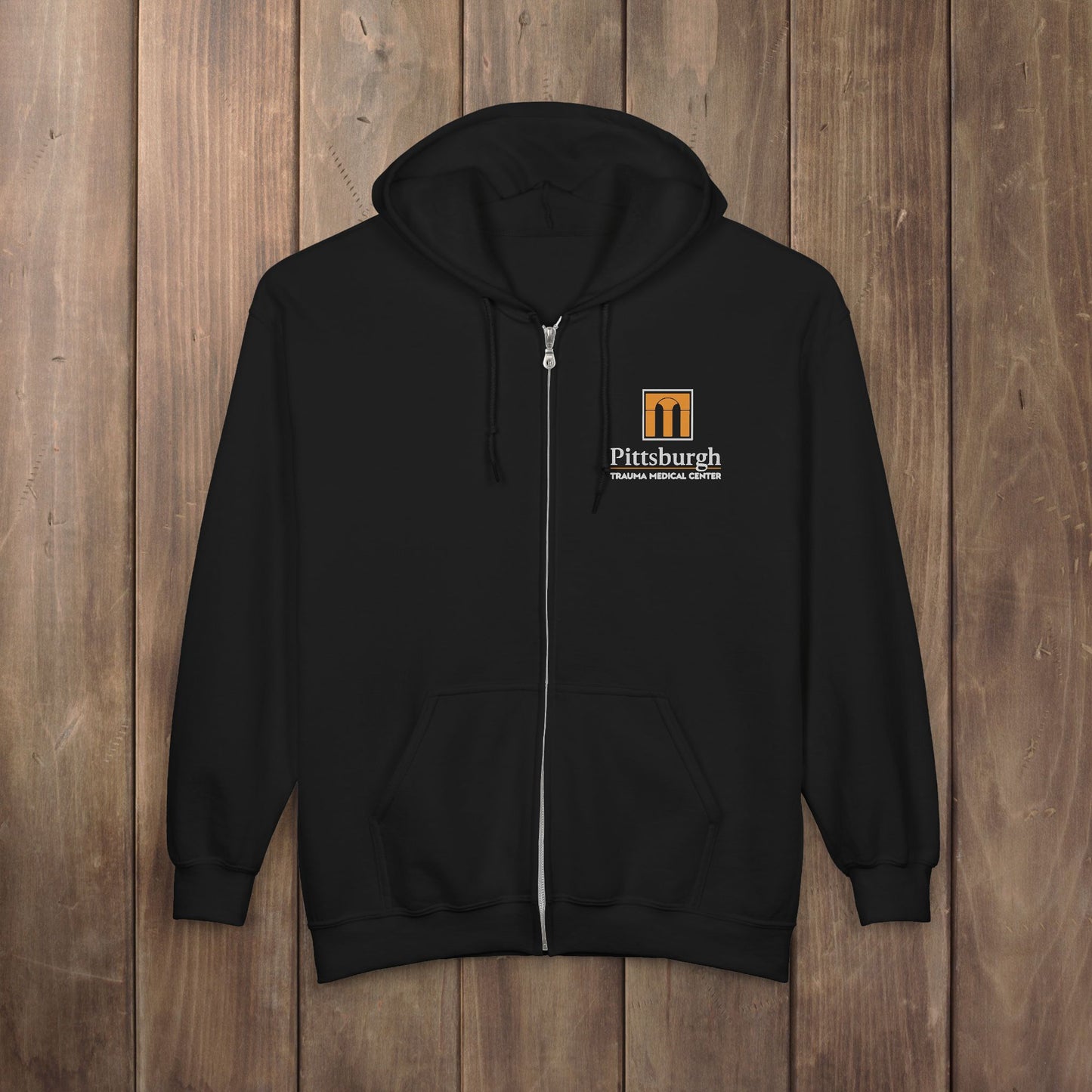 Black full-zip hoodie with the Pittsburgh Trauma Medical Center (PTMC) logo from The Pitt, printed on the left chest
