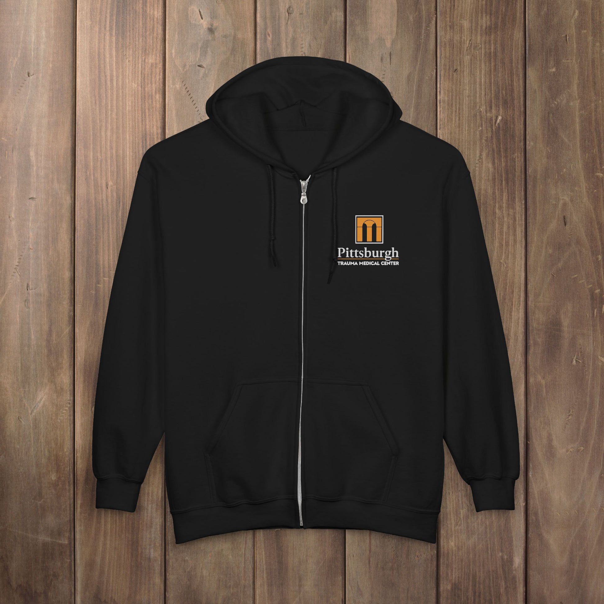Black full-zip hoodie with the Pittsburgh Trauma Medical Center (PTMC) logo from The Pitt, printed on the left chest