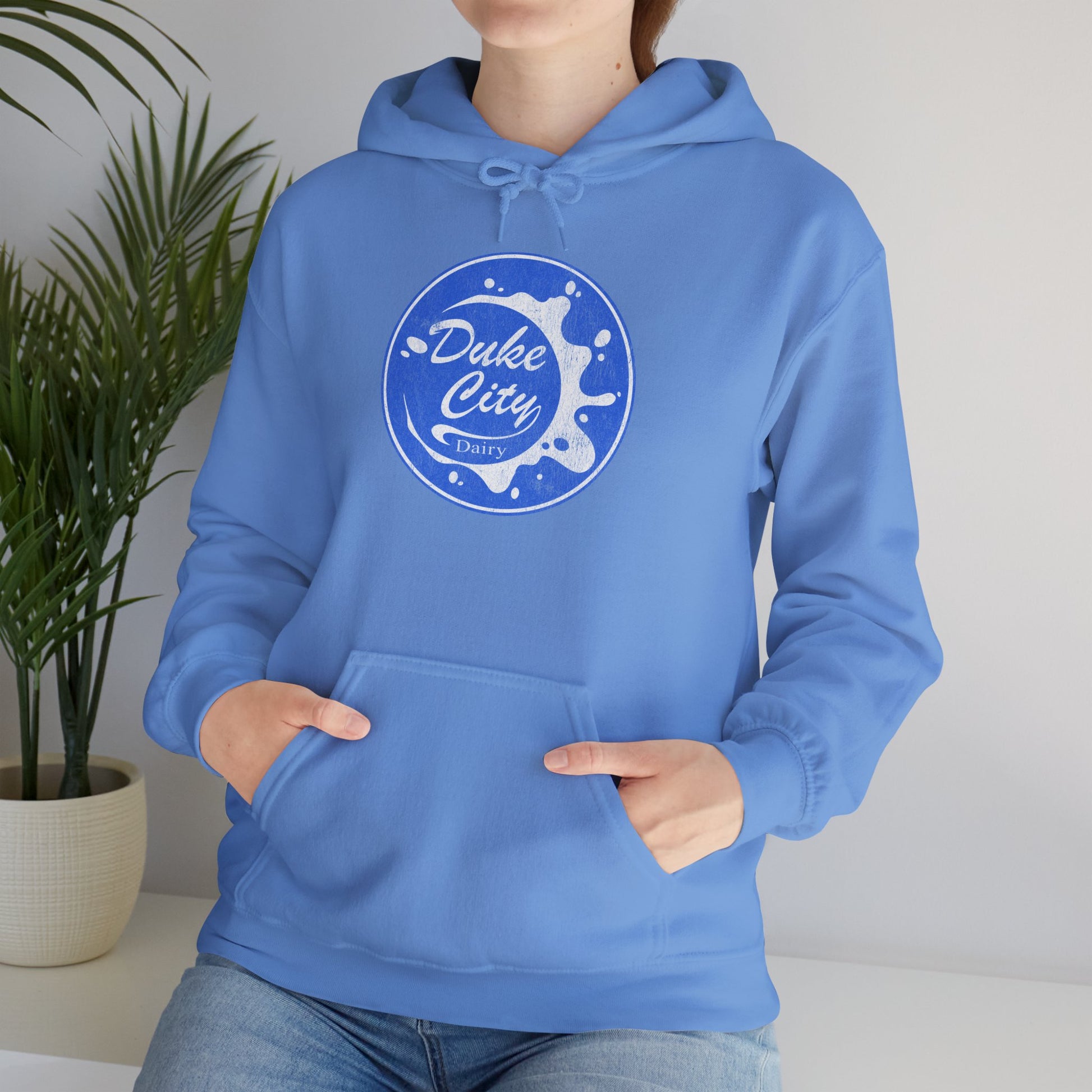 Woman wearing light blue hoodie with 'Duke City Dairy' logo from Pluribus.