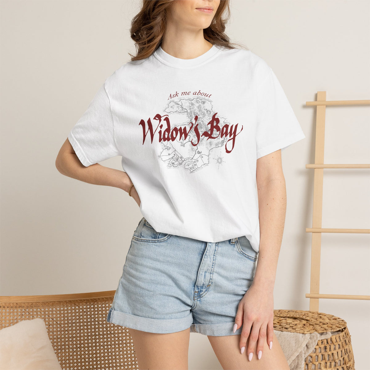 Woman wearing white Comfort Colors tee with a vintage island map and antique "Ask Me About Widow's Bay" type from the Apple TV show