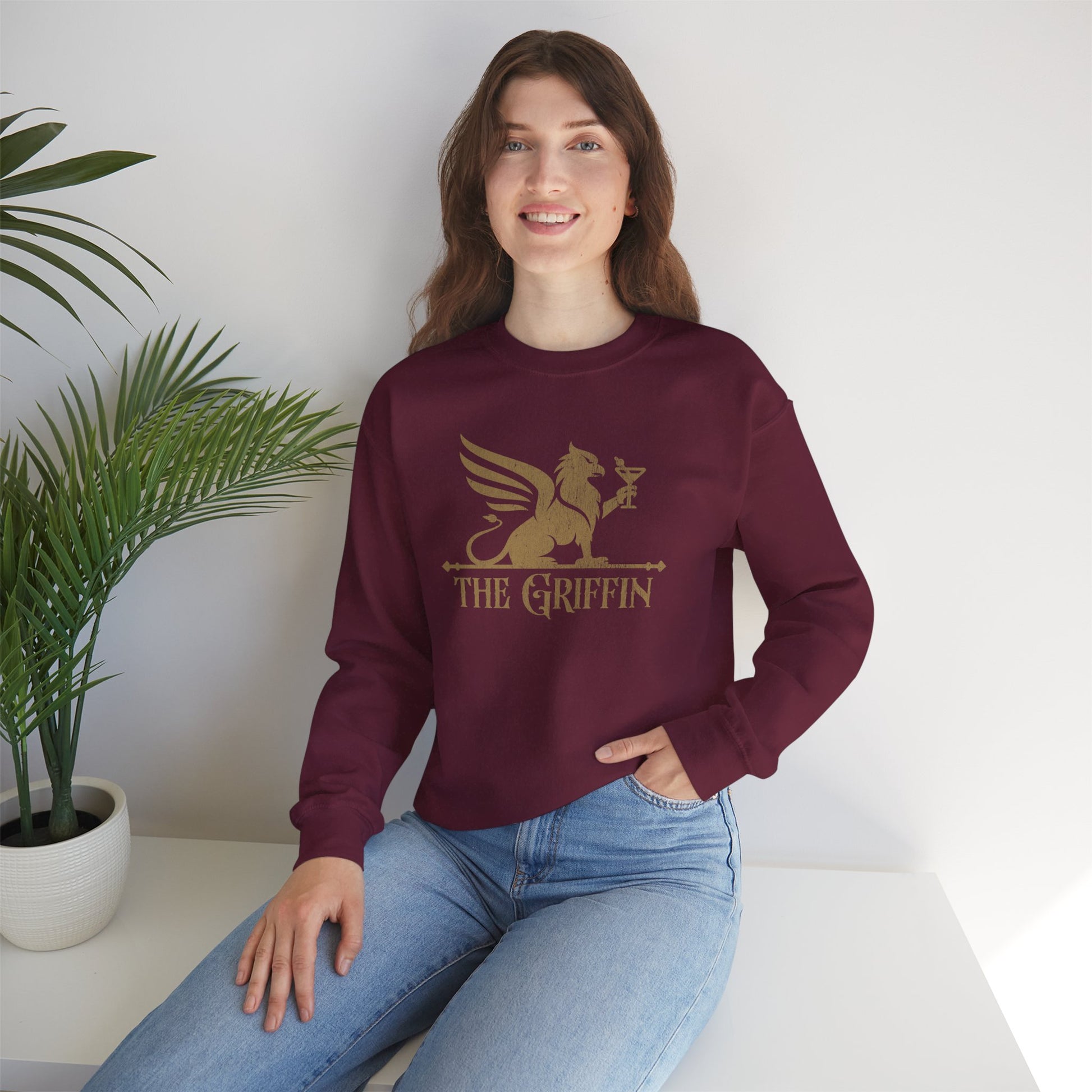 Woman wearing maroon crewneck sweatshirt with vintage distressed The Griffin Bar logo graphic inspired by New Girl