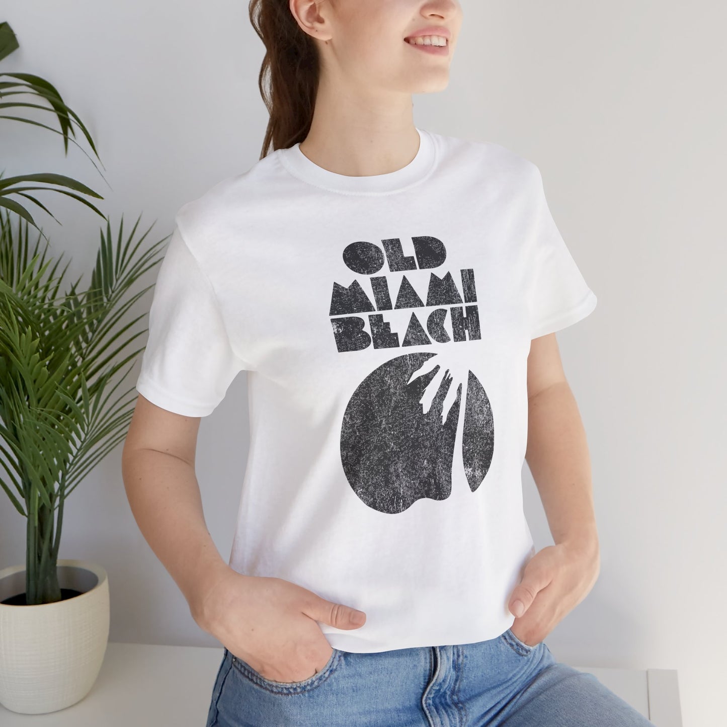 woman wearing white Bella+Canvas 3001 T-shirt with distressed “Old Miami Beach” graphic, inspired by Julia Garner’s shirt in Weapons movie.