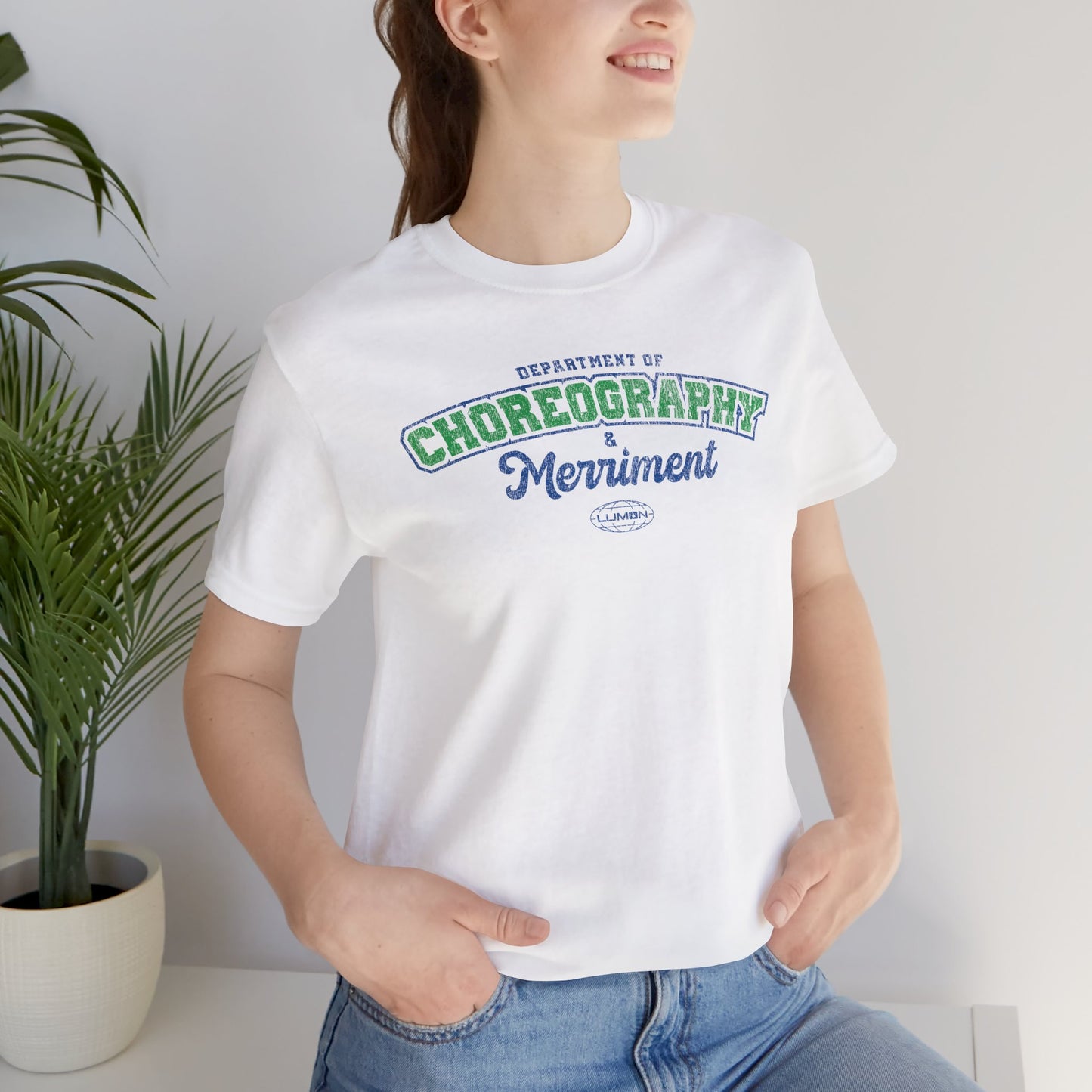 Female model wearing a white Soft Bella+Canvas 3001 short-sleeve t-shirt featuring the Department of Choreography and Merriment logo graphic inspired by the TV show Severance and Lumon Industries in a vintage distressed style, sold by ScriptedBrand.