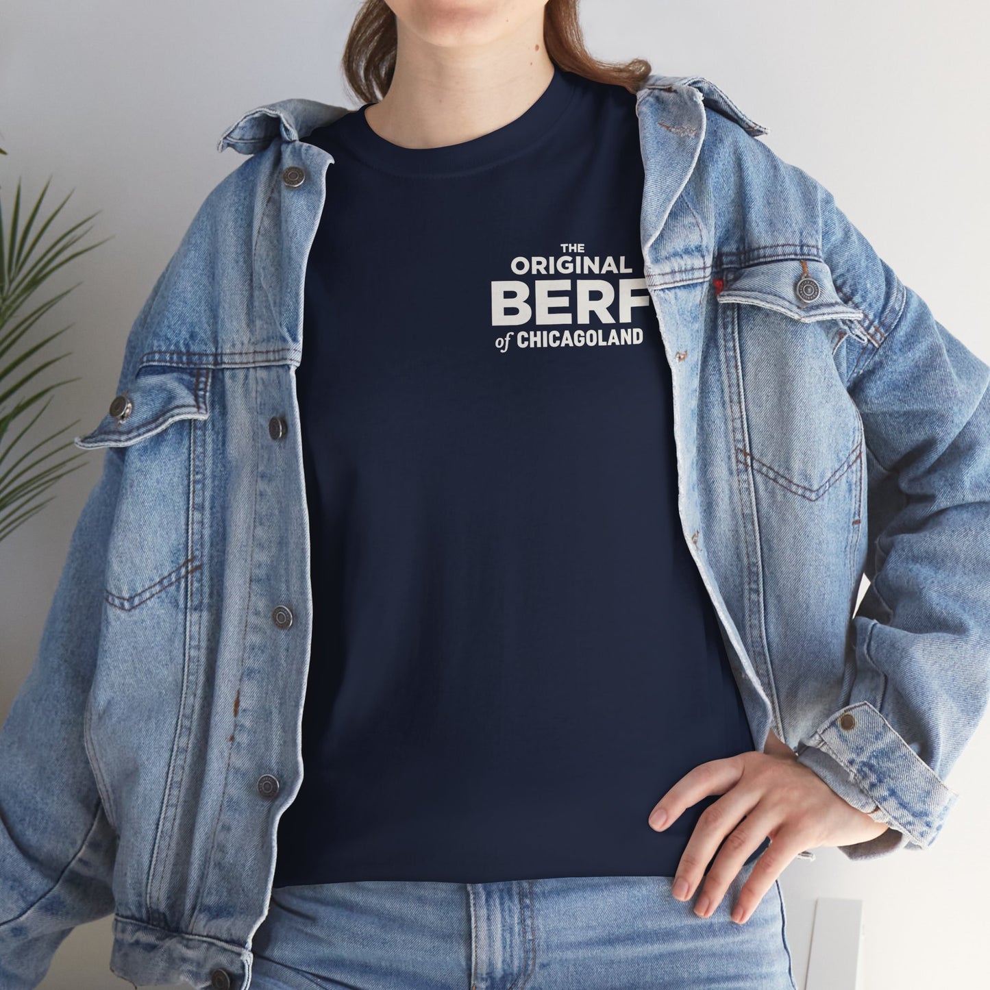 Person wearing a navy t-shirt with white text and a denim jacket indoors.