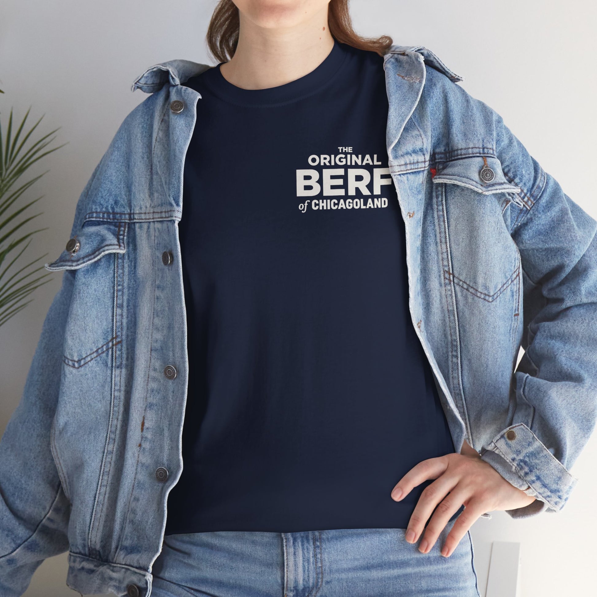 Person wearing a navy t-shirt with white text and a denim jacket indoors.