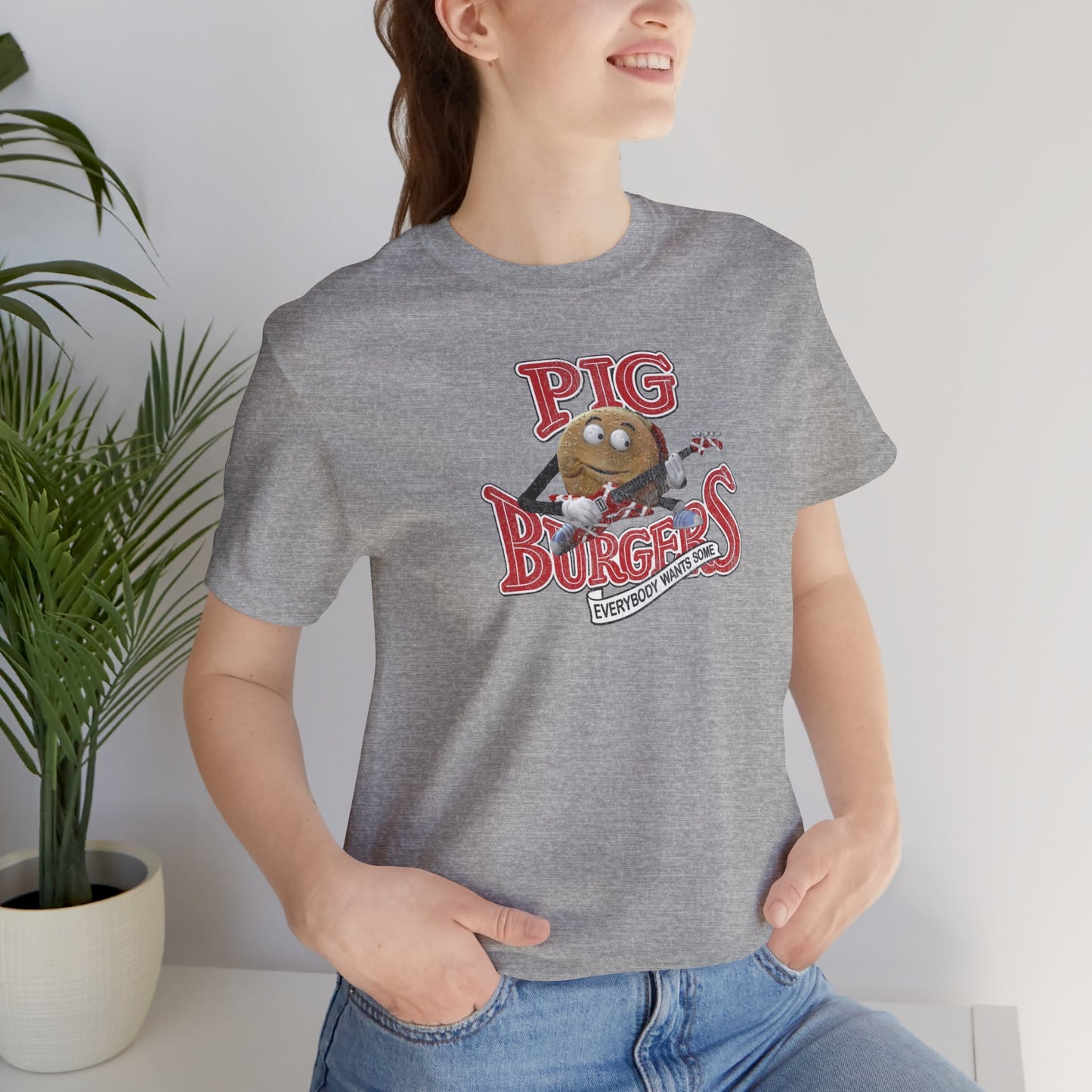 Woman wearing Heather gray soft Bella Canvas Tee featuring vintage Pig Burgers logo with Van Halen guitar from the movie Better Off Dead.