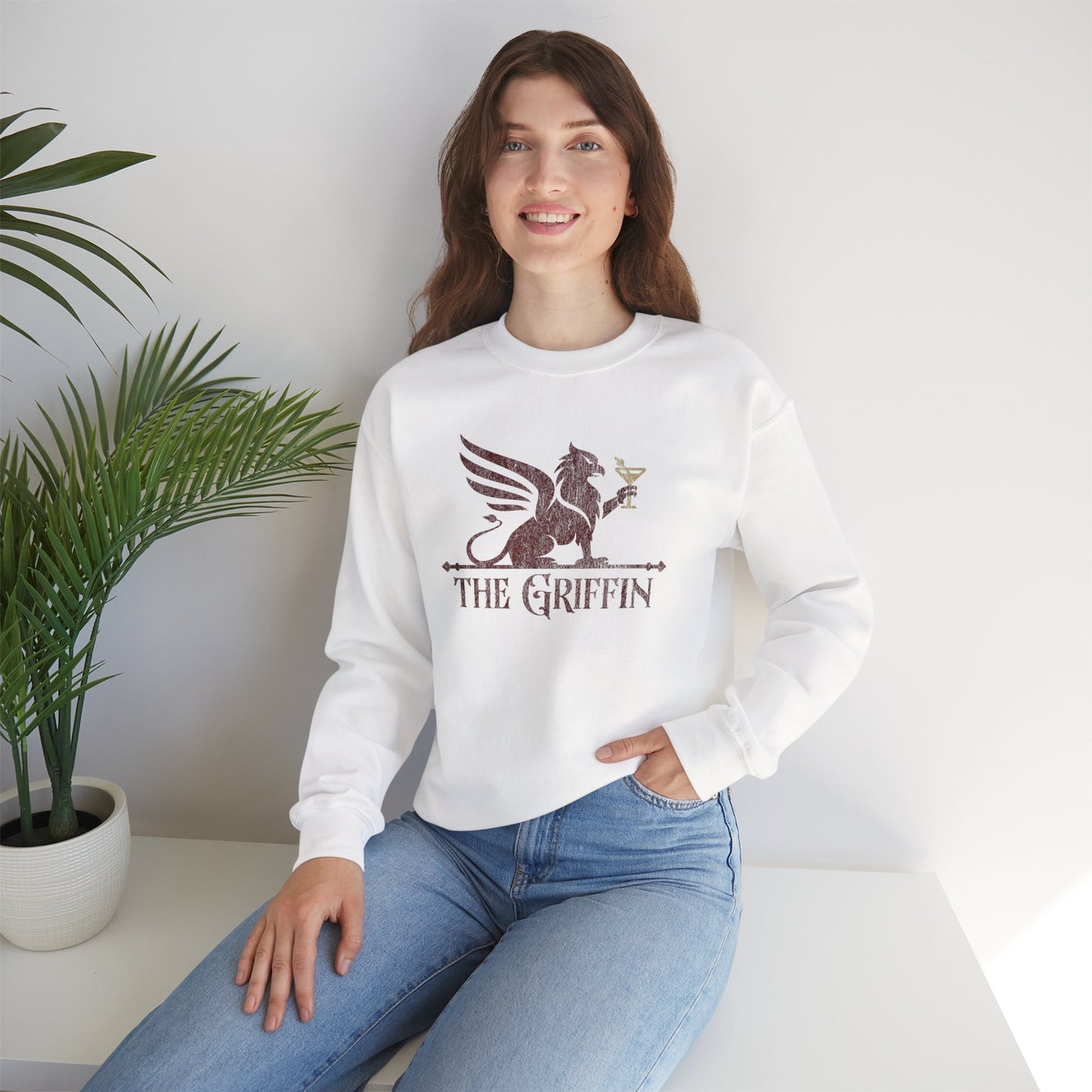 Woman wearing white crewneck sweatshirt with vintage distressed The Griffin Bar logo graphic inspired by New Girl