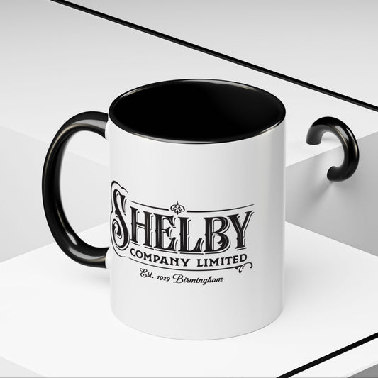 Front Angled view of a 11 oz White Ceramic Mug with black handle/interior featuring the fictional Shelby Company Limited Logo from the TV show Peaky Blinders printed on both sides. Graphic is designed by ScriptedBrand and includes the text "Est. 1919 Birmingham"