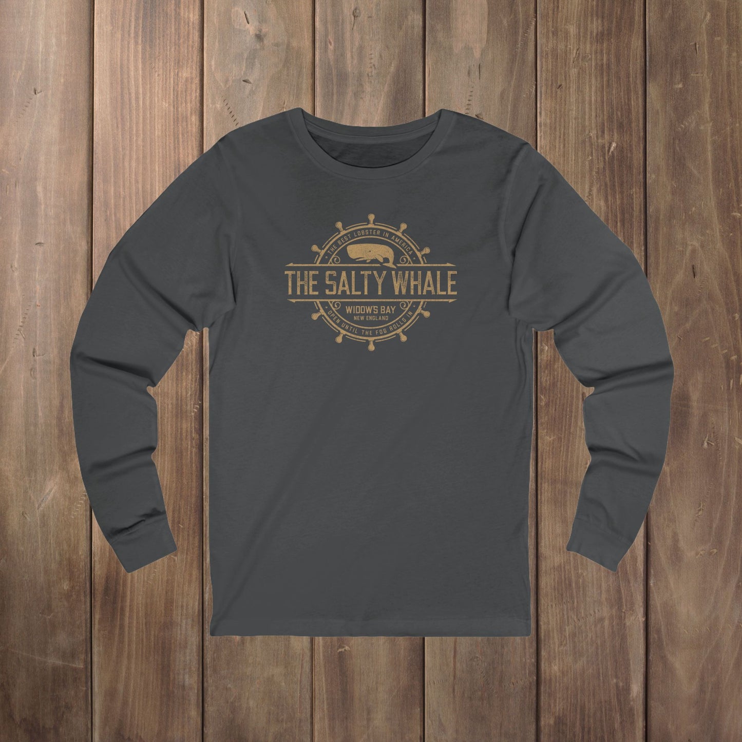 Dark gray long-sleeve tee with the gold distressed Salty Whale maritime crest logo from Widow's Bay, New England