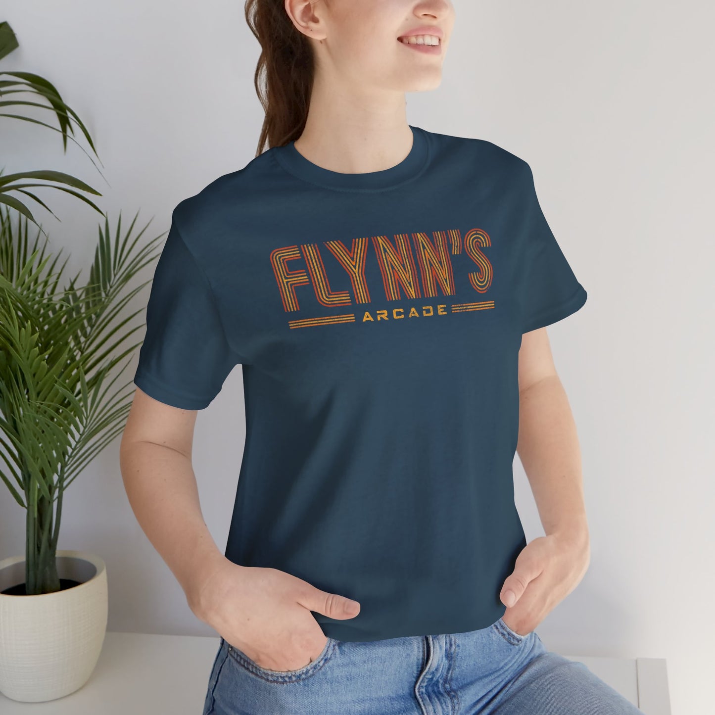 Person wearing a teal  blue t-shirt with vintage distressed 'Flynn’s Arcade' neon sign logo inspired by TRON