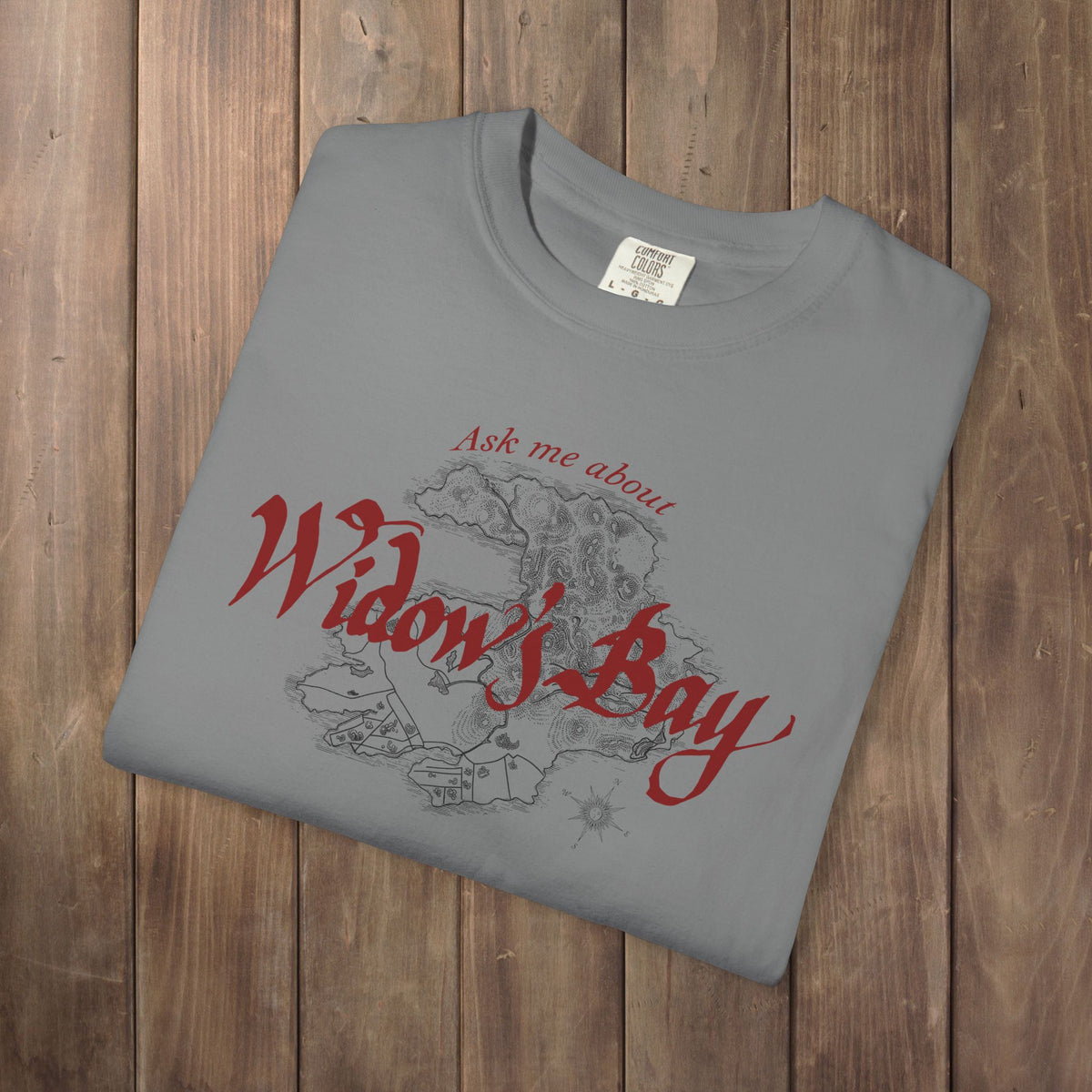 Folded grey Comfort Colors tee with a vintage island map and antique "Ask Me About Widow's Bay" type from the Apple TV show