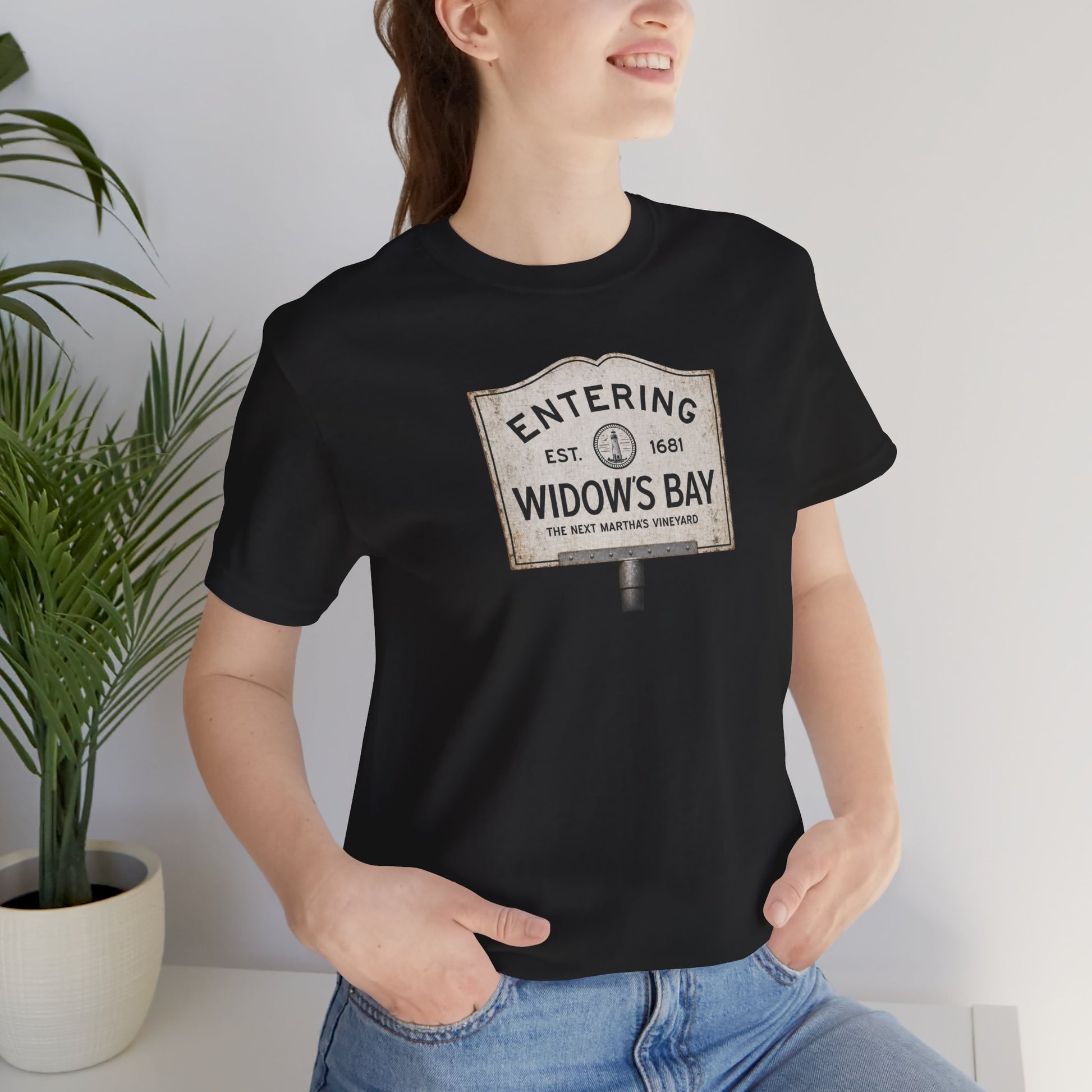 Woman wearing Black 'Entering Widow's Bay' vintage town sign t-shirt inspired by Apple TV series, soft Bella+Canvas cotton New England tee