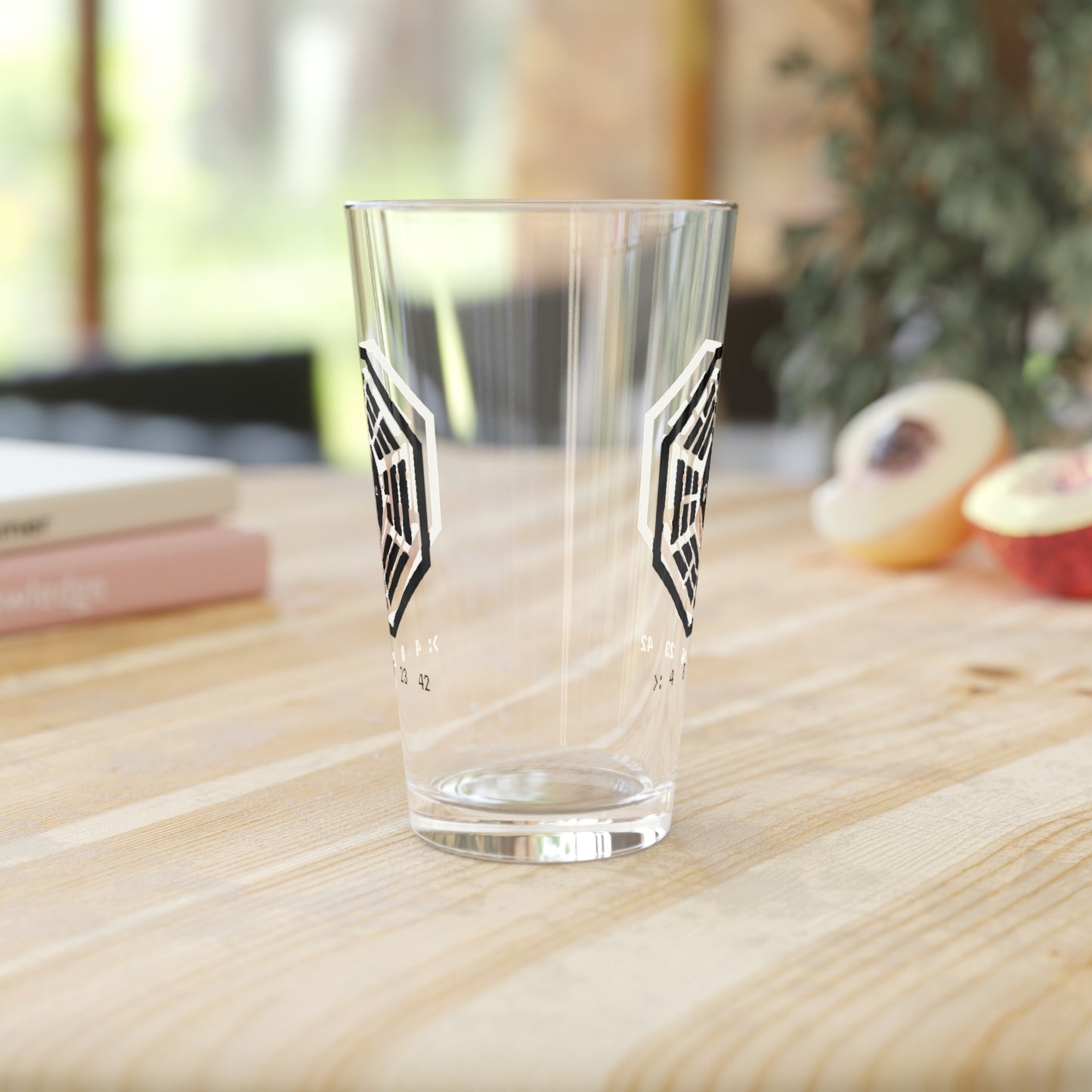 Side view of clear 16 oz pint glass with Dharma Initiative Swan Station logo and hatch numbers from Lost Show, on a white background