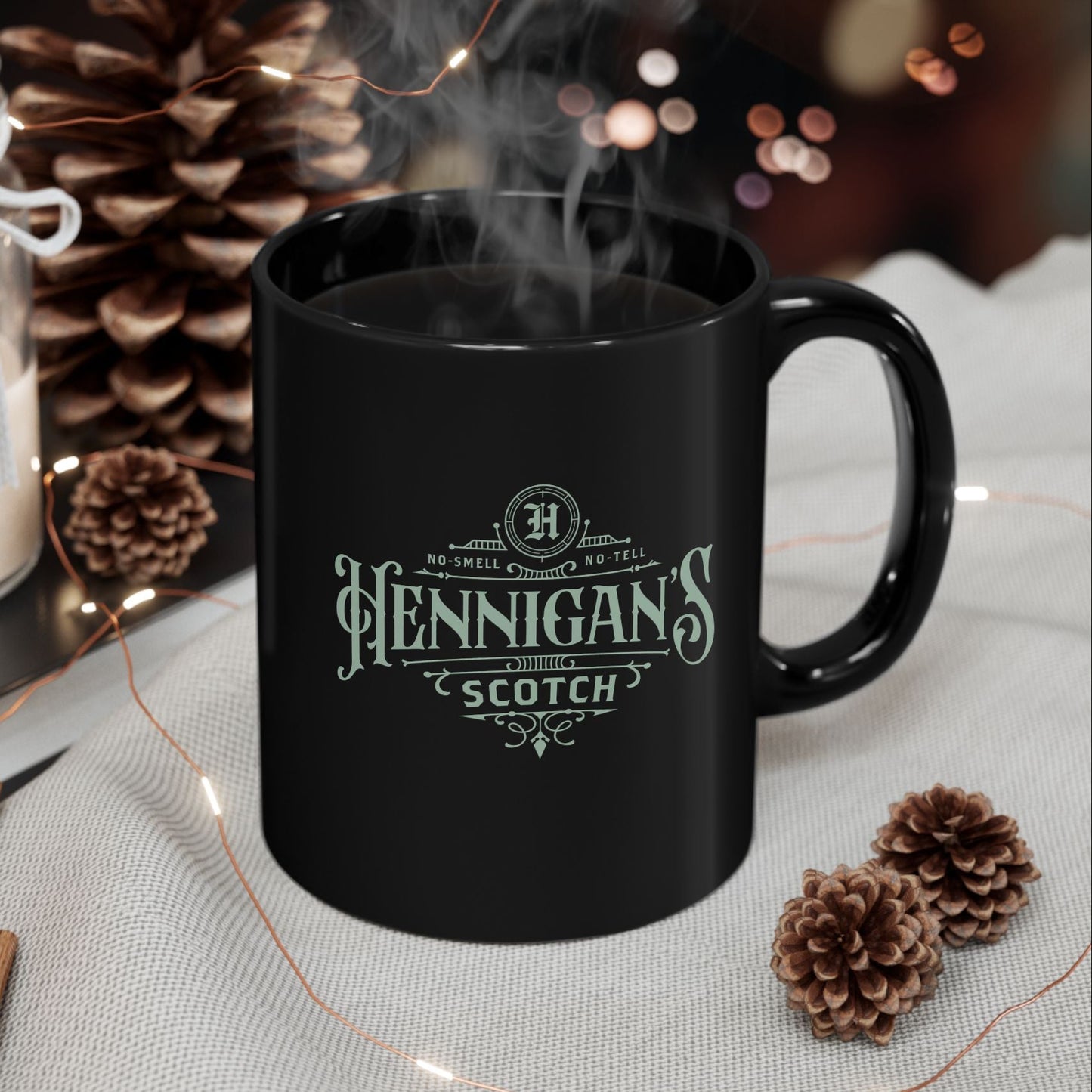 Black mug with 'Hennigan's Scotch' logo on a table with decorative items