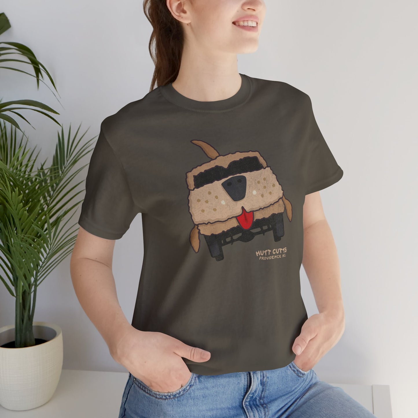 Woman wearing army Bella+Canvas tee with vintage Mutt Cutts dog van graphic inspired by Dumb and Dumber movie.