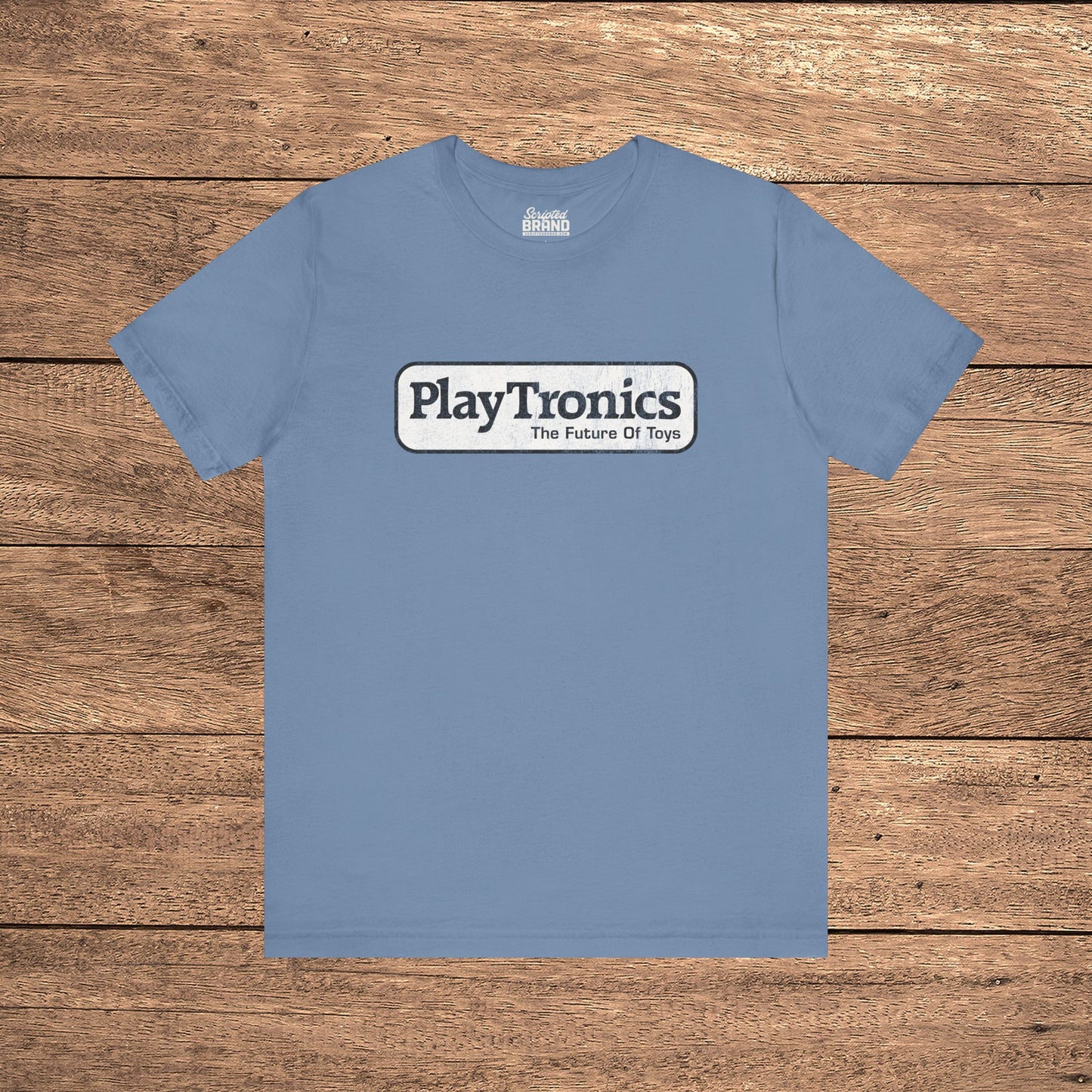 Steel blue PlayTronics Sneakers movie logo t-shirt on Bella+Canvas 3001, vintage distressed print, shown on wood floor.