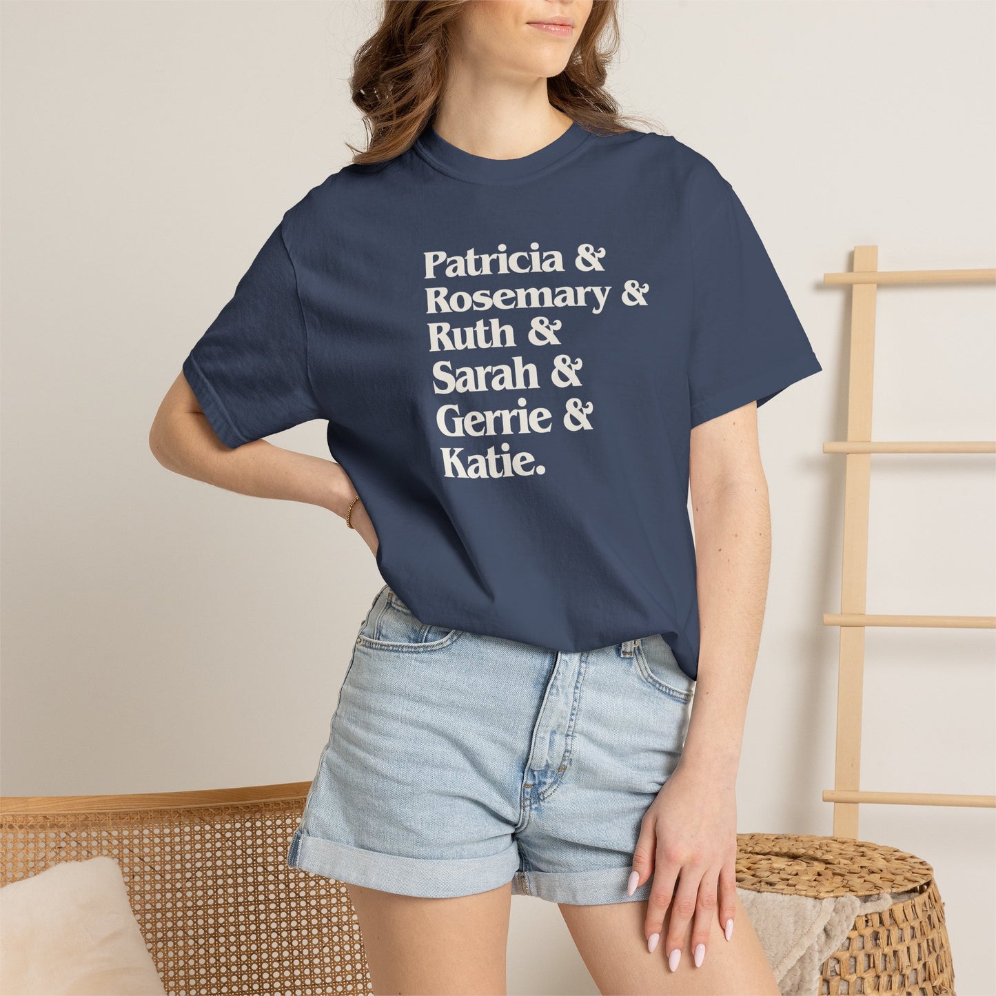 Woman wearing midnight blue Comfort Colors tee listing the women of Widow's Bay: Patricia, Rosemary, Ruth, Sarah, Gerrie, and Katie