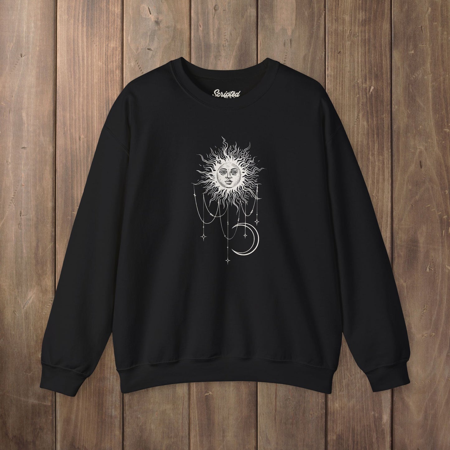 Black crewneck sweatshirt with boho celestial sun face, stars, and crescent moon design worn by Patricia in Widow's Bay