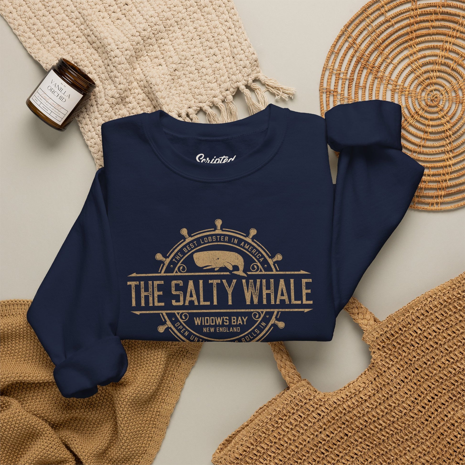 Folded Navy blue Gildan crewneck sweatshirt with the distressed Salty Whale maritime crest logo from TV show Widow's Bay