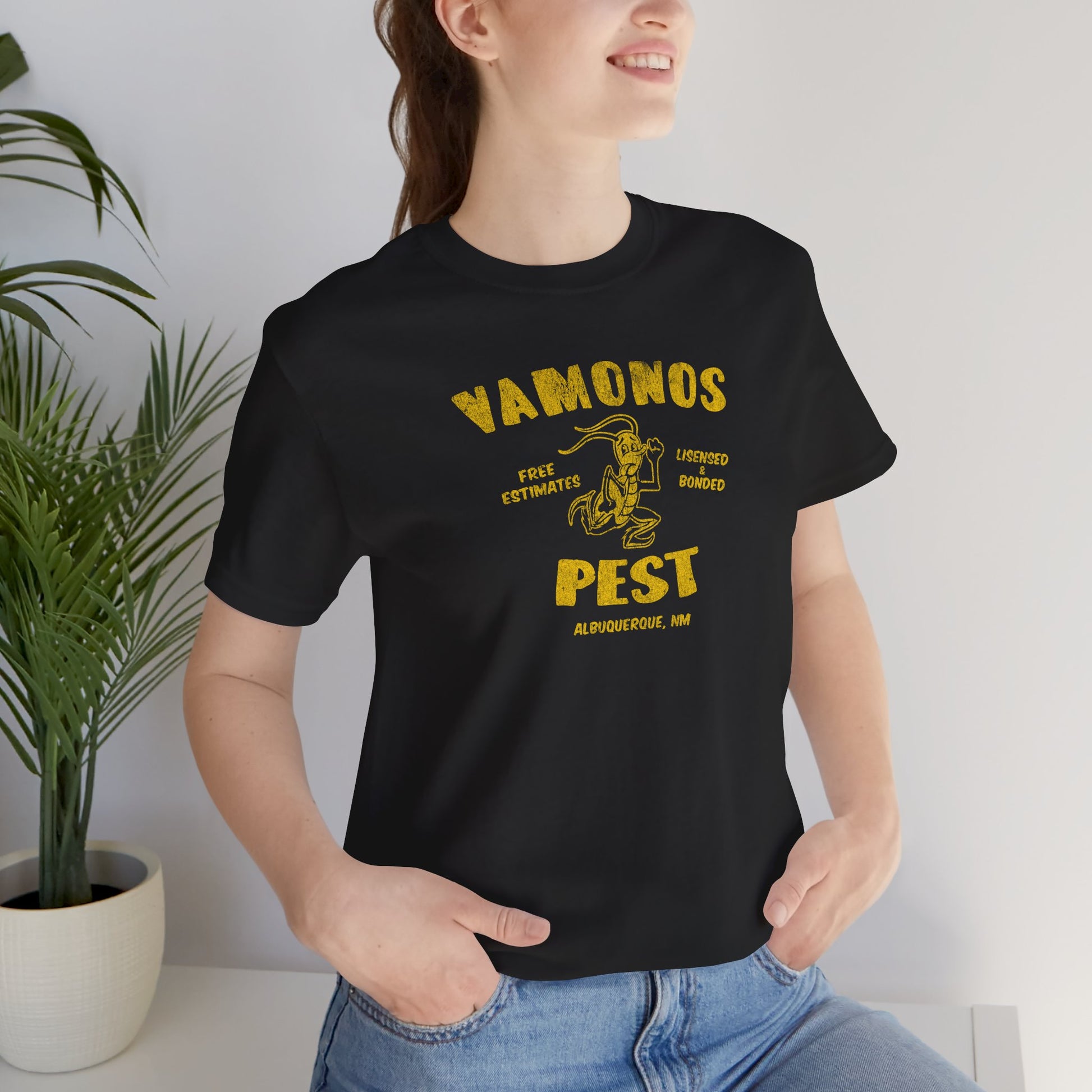 Female model wearing a black colored soft Bella+Canvas 3001 short-sleeve t-shirt featuring the Vamonos Pest Exterminators logo from the TV show Breaking Bad in a vintage distressed style, sold by ScriptedBrand.