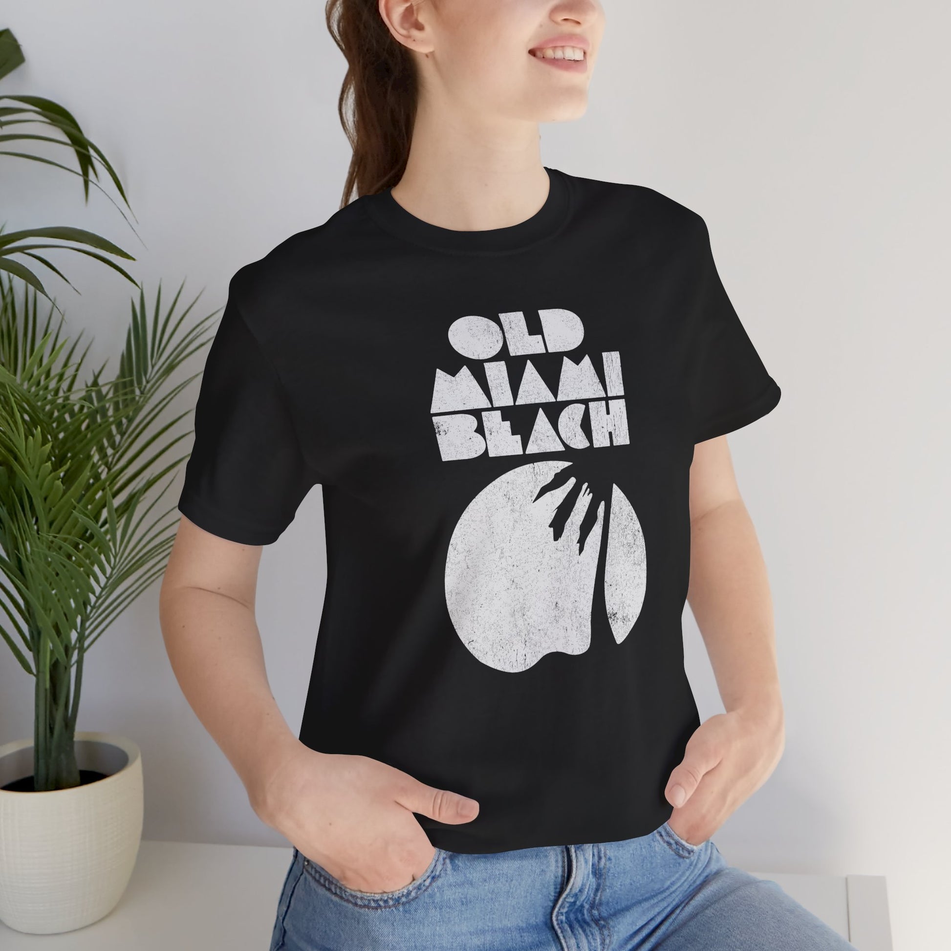 woman wearing Black Bella+Canvas 3001 T-shirt with distressed “Old Miami Beach” graphic, inspired by Julia Garner’s shirt in Weapons movie.