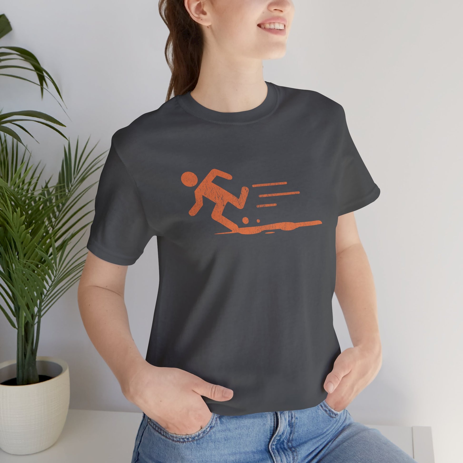 Woman wearing asphalt dark gray tee with orange vintage distressed Portal 2 Propulsion Gel icon of a figure sprinting fast