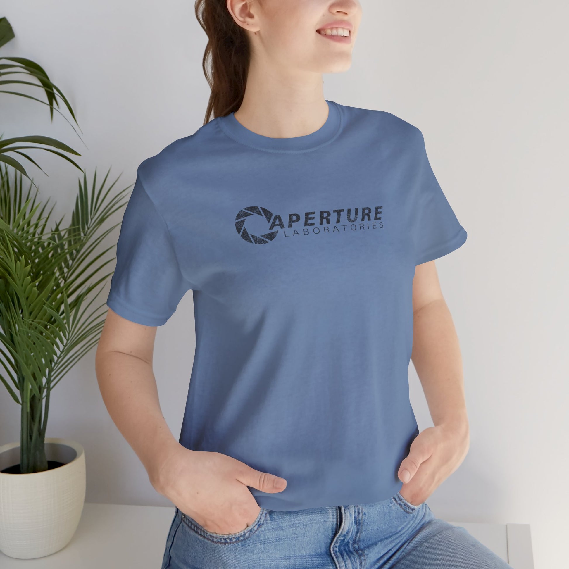 Woman wearing steel blue Bella Canvas t-shirt with the Aperture Laboratories logo from the video game Portal and Portal 2 in a vintage distressed style.