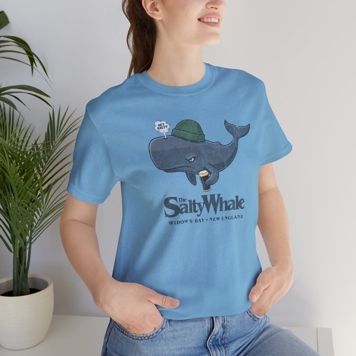 Woman wearing Ocean blue 'The Salty Whale' cartoon mascot t-shirt inspired by Widow's Bay Apple TV series, soft Bella+Canvas cotton pub fan tee