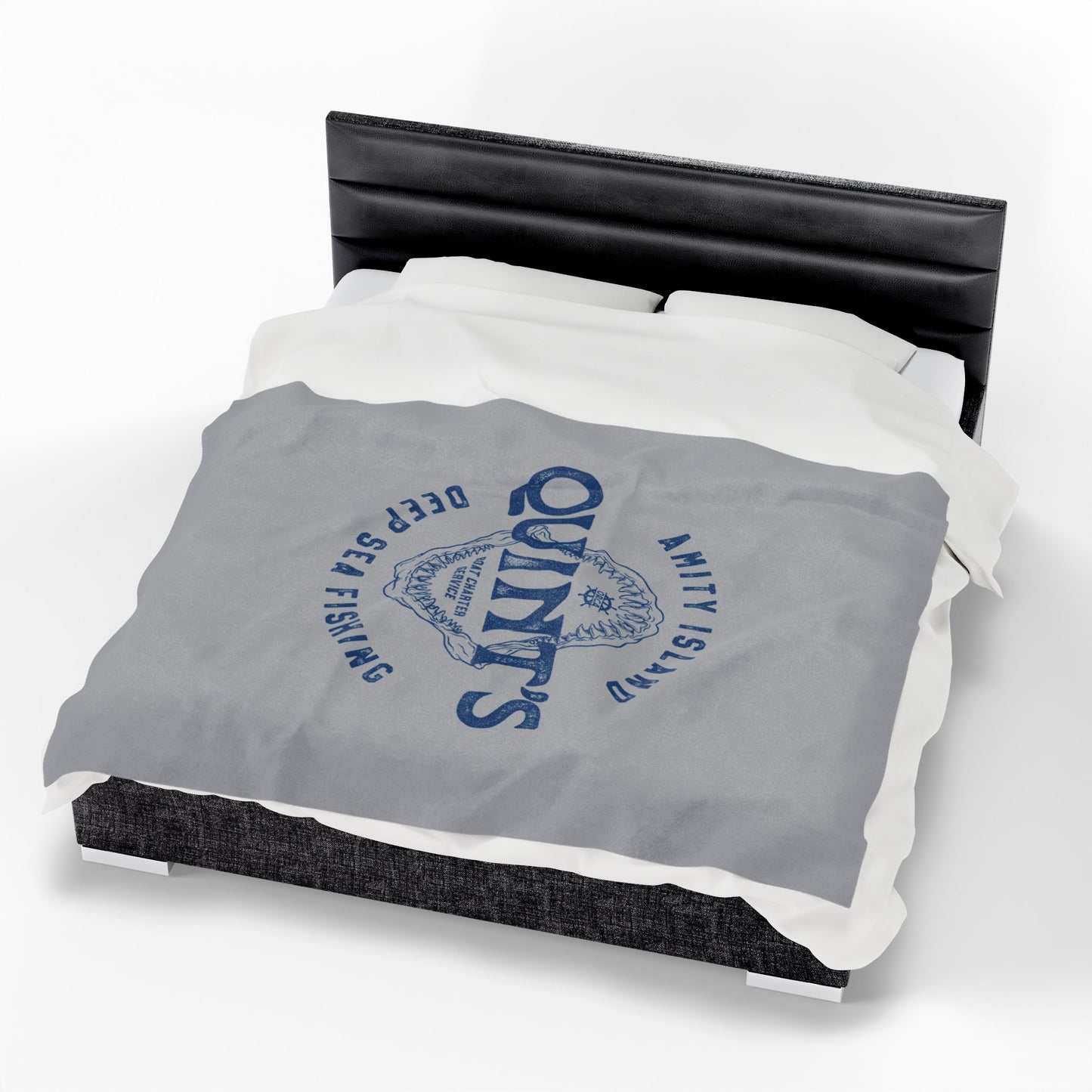 60x80 large Gray velveteen plush blanket with vintage blue Quint’s Deep Sea Fishing logo inspired by Jaws, laid on a queen sized bed.