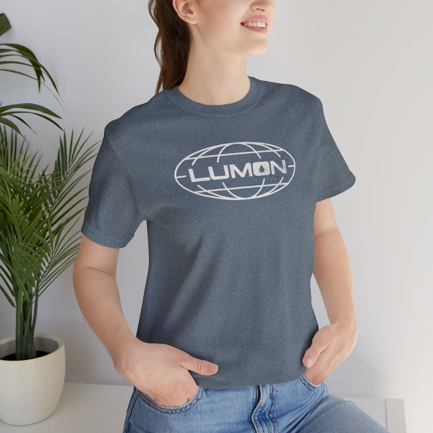 Woman wearing heather slate blue Bella+Canvas tee with a vintage distressed Lumon Industries globe logo from the Apple TV show Severance