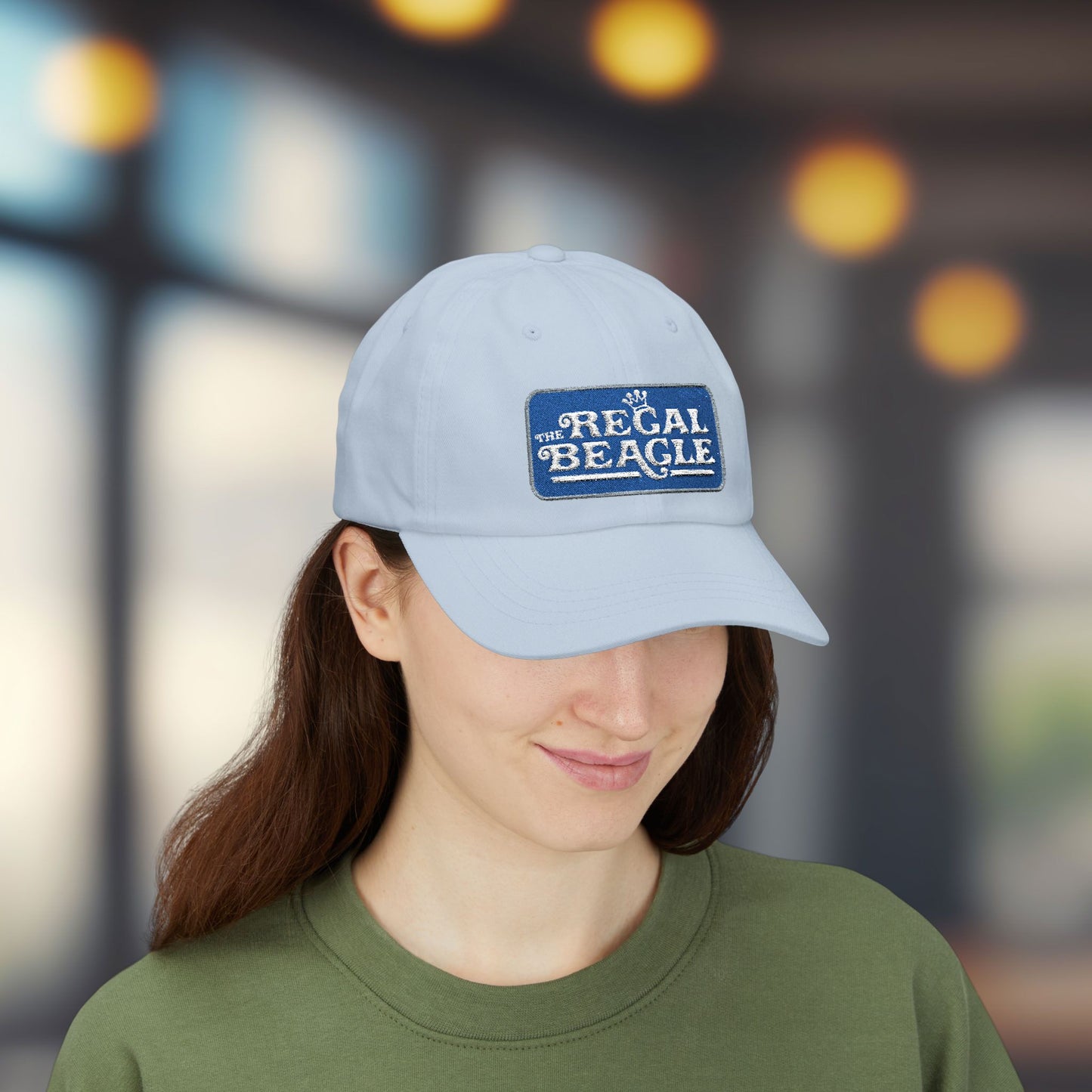 Woman wearing light blue dad cap with embroidered Regal Beagle patch logo, Three's Company inspired fictional bar merch
