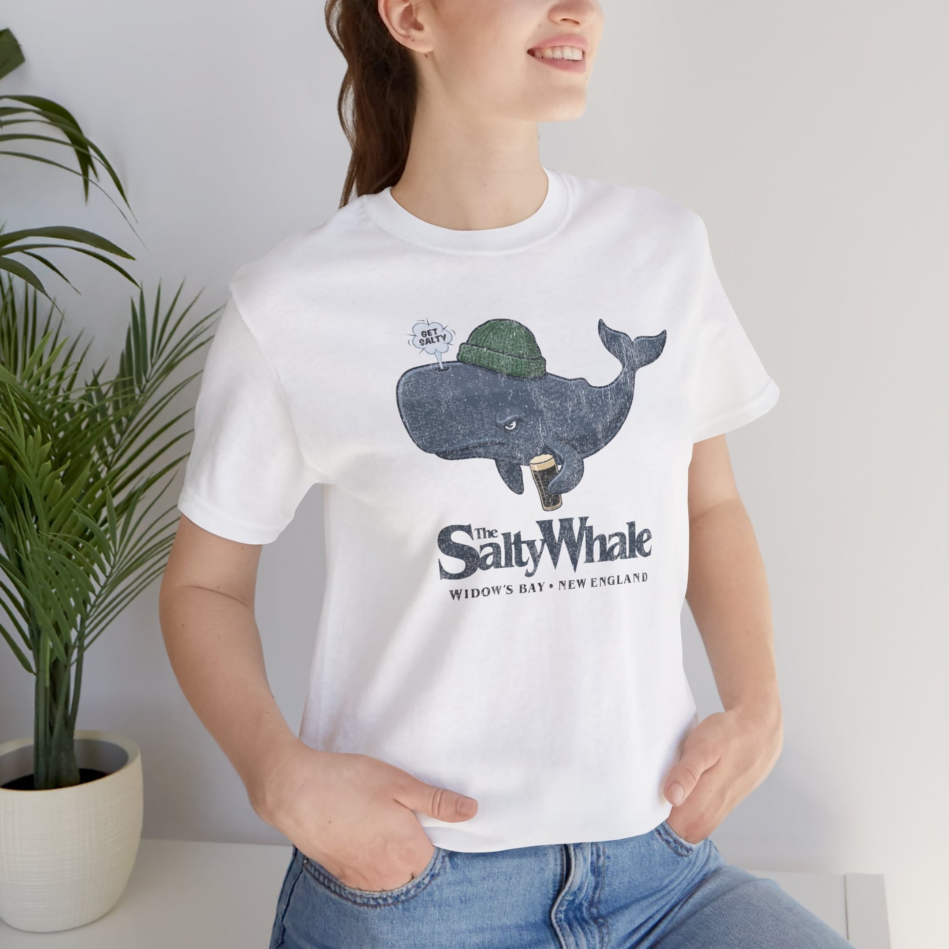 Woman wearing white 'The Salty Whale' cartoon mascot t-shirt inspired by Widow's Bay Apple TV series, soft Bella+Canvas cotton pub fan tee