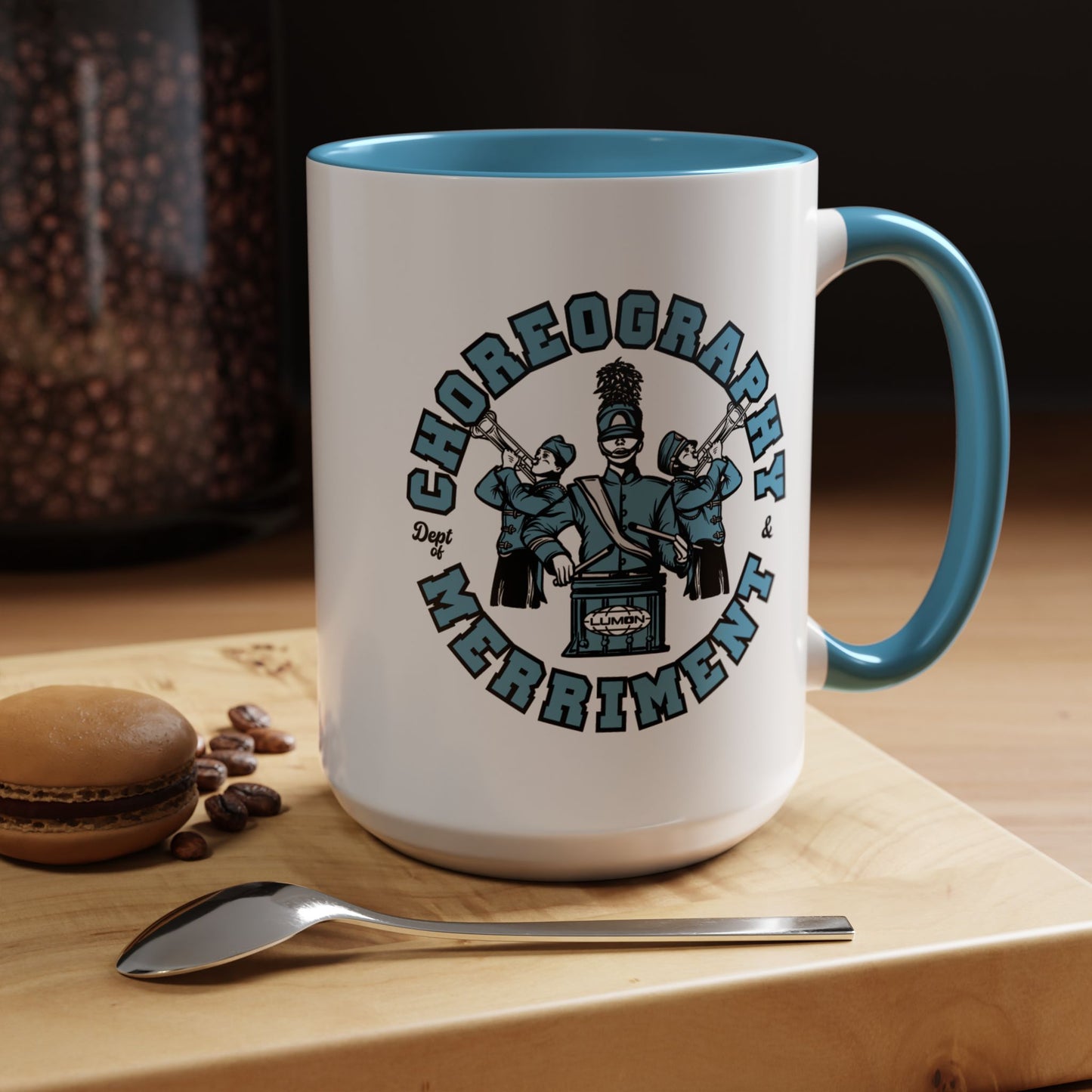 15 oz White ceramic accent mug with blue handle featuring Severance Dept. of Choreography & Merriment graphic, shown on a table.