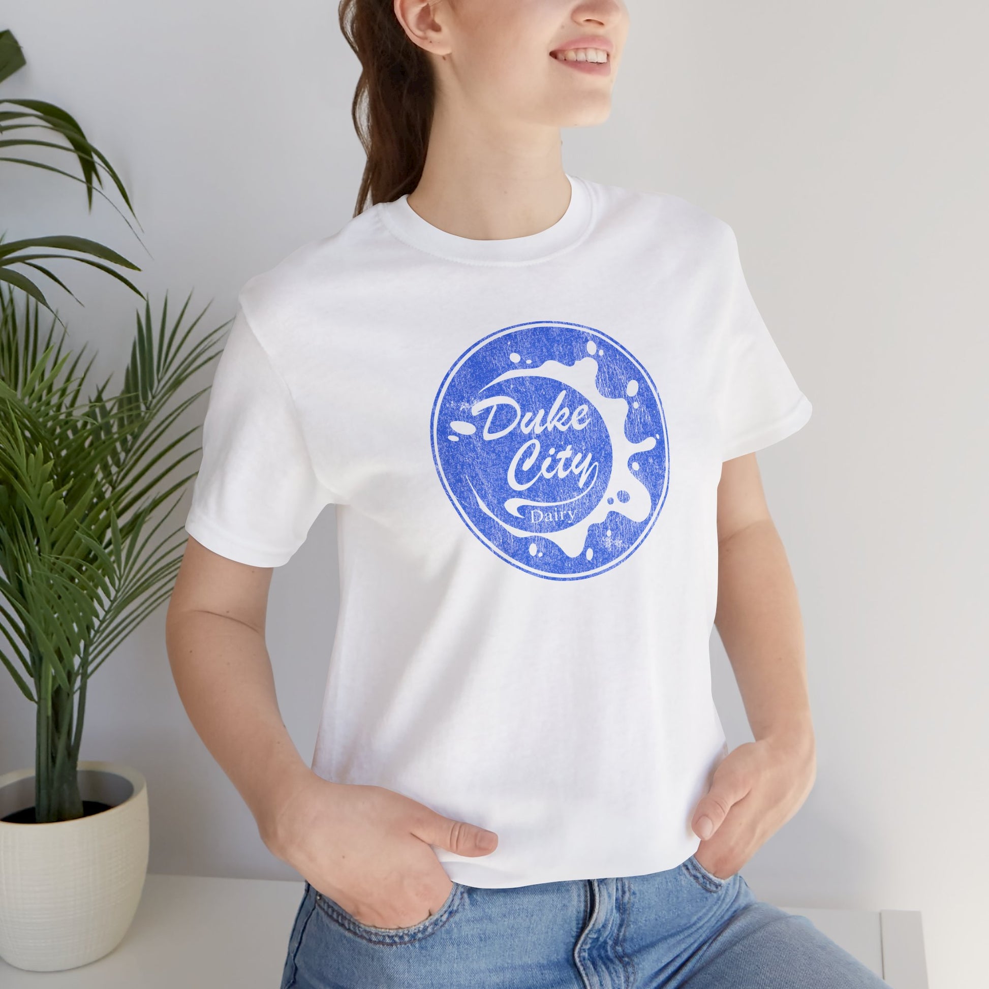Woman wearing white t-shirt with vintage distressed Duke City Dairy logo inspired by TV Show Pluribus.