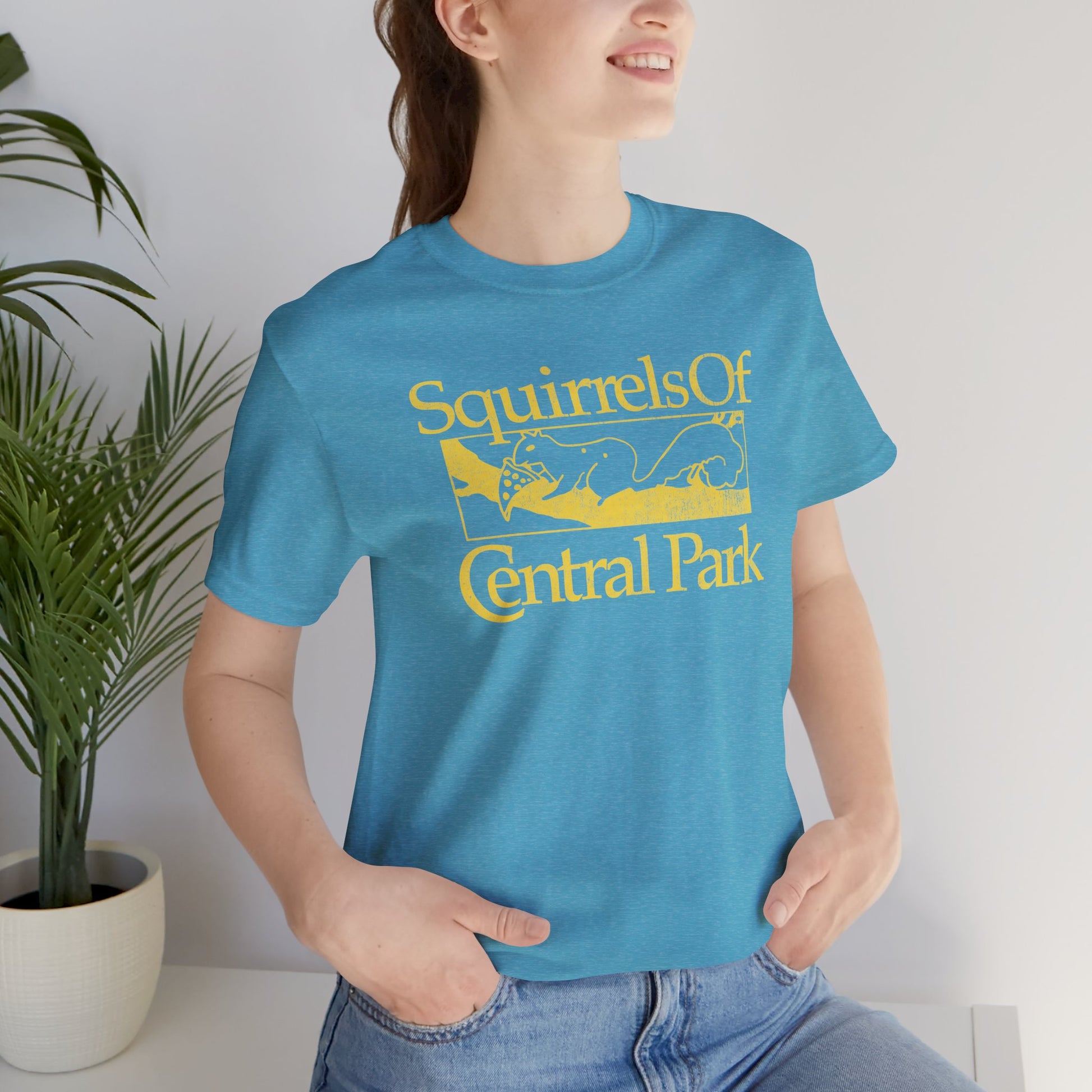 Woman wearing heather aqua blue unisex t-shirt with distressed “Squirrels of Central Park” graphic, worn by Eva Garvey in the show Bad Sisters.