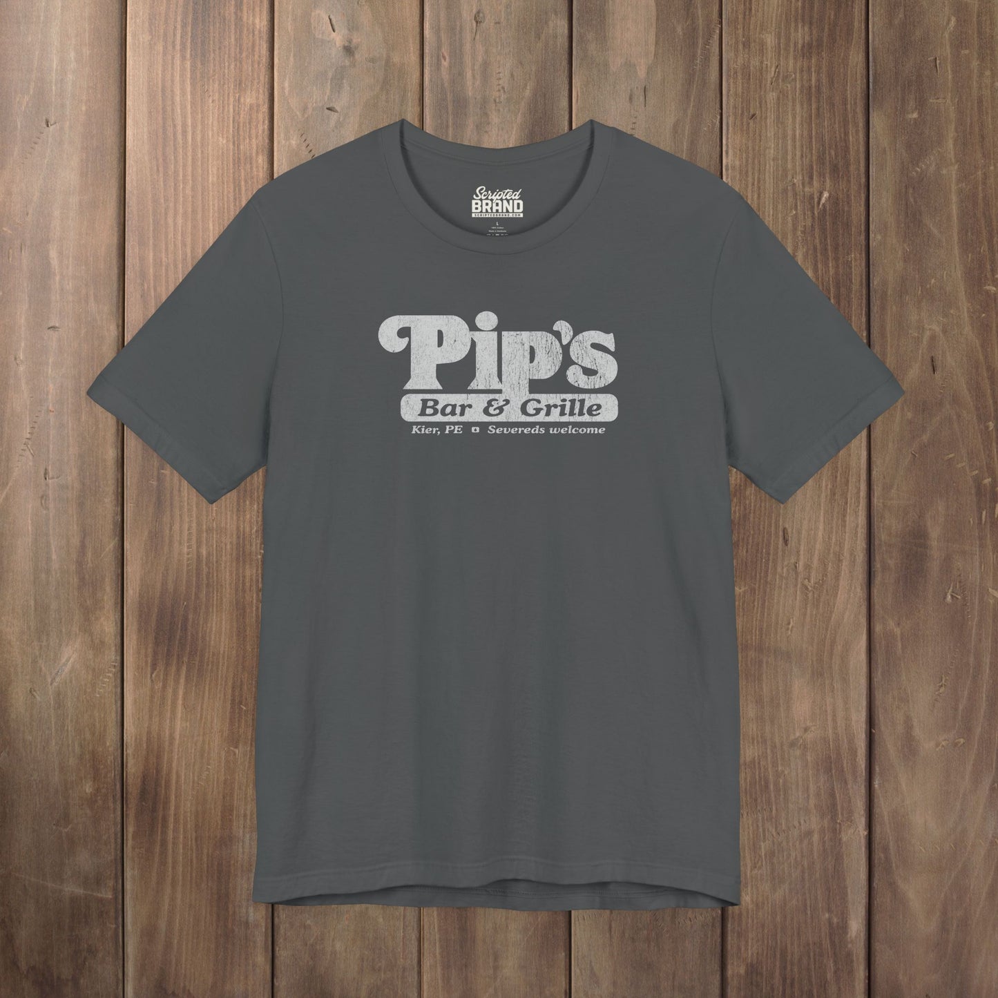 Dark gray Bella+Canvas t-shirt with the Pips Bar and Grill logo from the TV show Severance in a vintage distressed style.