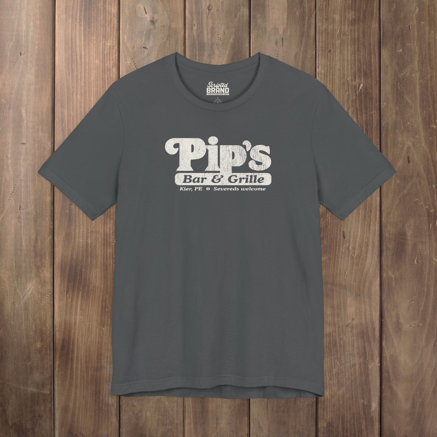 Dark gray Bella+Canvas t-shirt with the Pips Bar and Grill logo from the TV show Severance in a vintage distressed style.