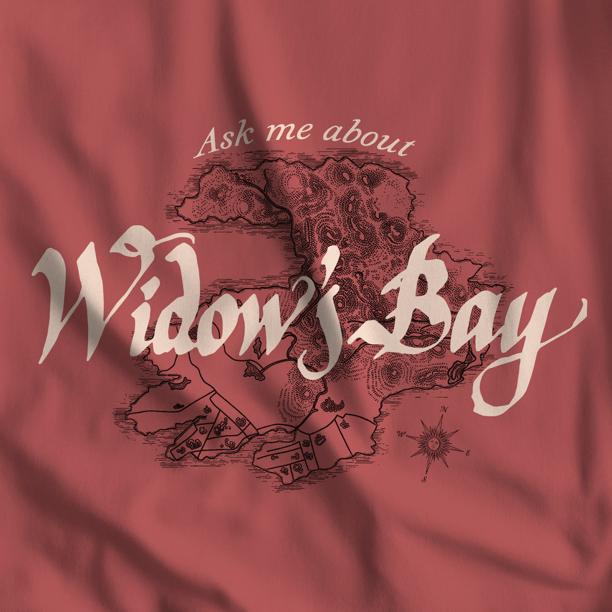 Closeup of Patricia crimson red Comfort Colors tee with a vintage island map and antique "Ask Me About Widow's Bay" type from the Apple TV show