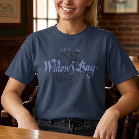 Person wearing midnight blue Comfort Colors tee with a vintage island map and antique "Ask Me About Widow's Bay" type from the Apple TV show