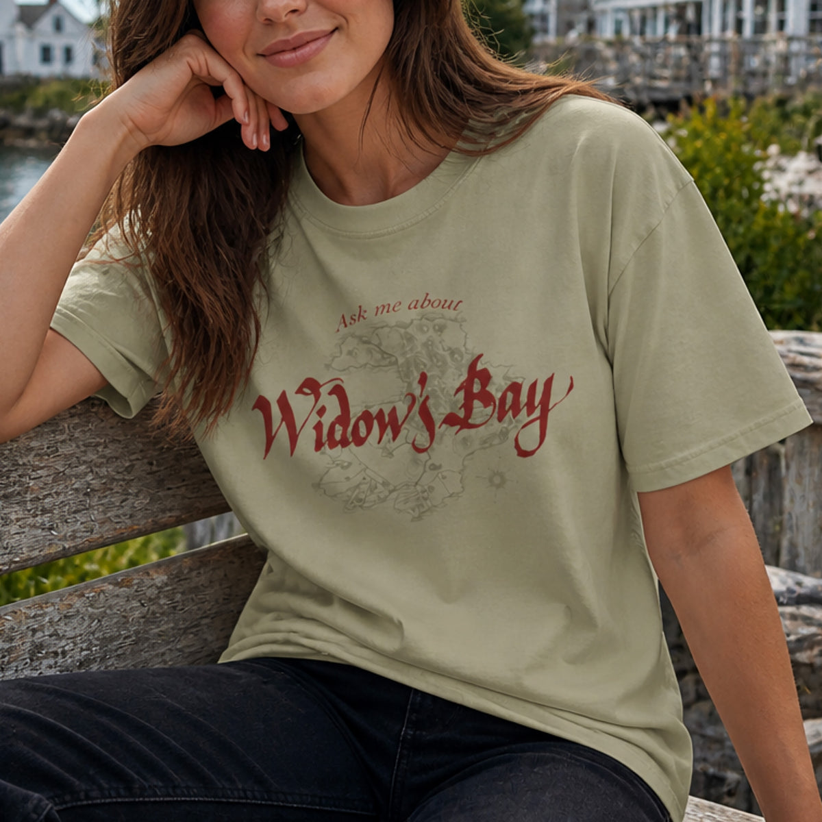 Person wearing khaki tan Comfort Colors tee with a vintage island map and antique "Ask Me About Widow's Bay" type from the Apple TV show