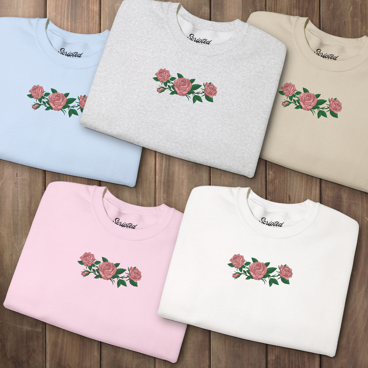 Five folded crewneck sweatshirts with three pink roses and green leaves printed across the chest, inspired by Ruth of Widow's Bay.