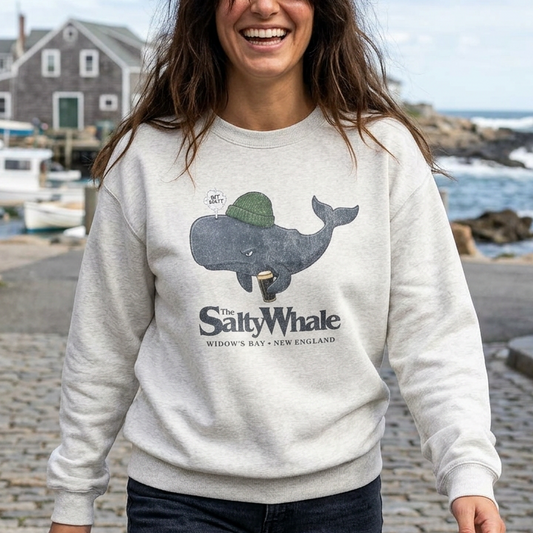 Person wearing ash colored The Salty Whale cartoon mascot crewneck sweatshirt inspired by Widow's Bay Apple TV series, vintage pub fan pullover