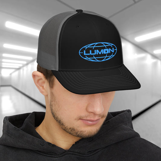 Man wearing black and charcoal Richardson 112 trucker cap with embroidered blue Lumon Industries logo inspired by Severance.