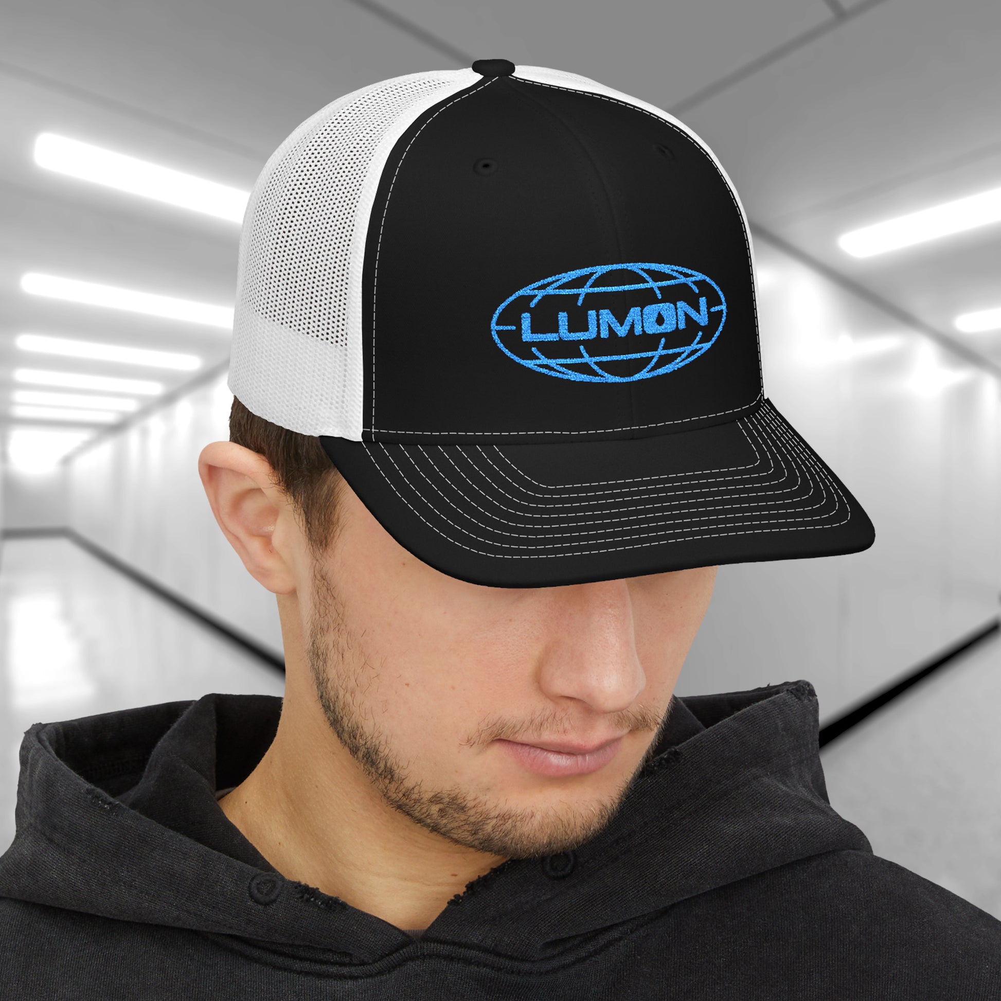 Man wearing black and white Richardson 112 trucker cap with embroidered blue Lumon Industries logo inspired by Severance.