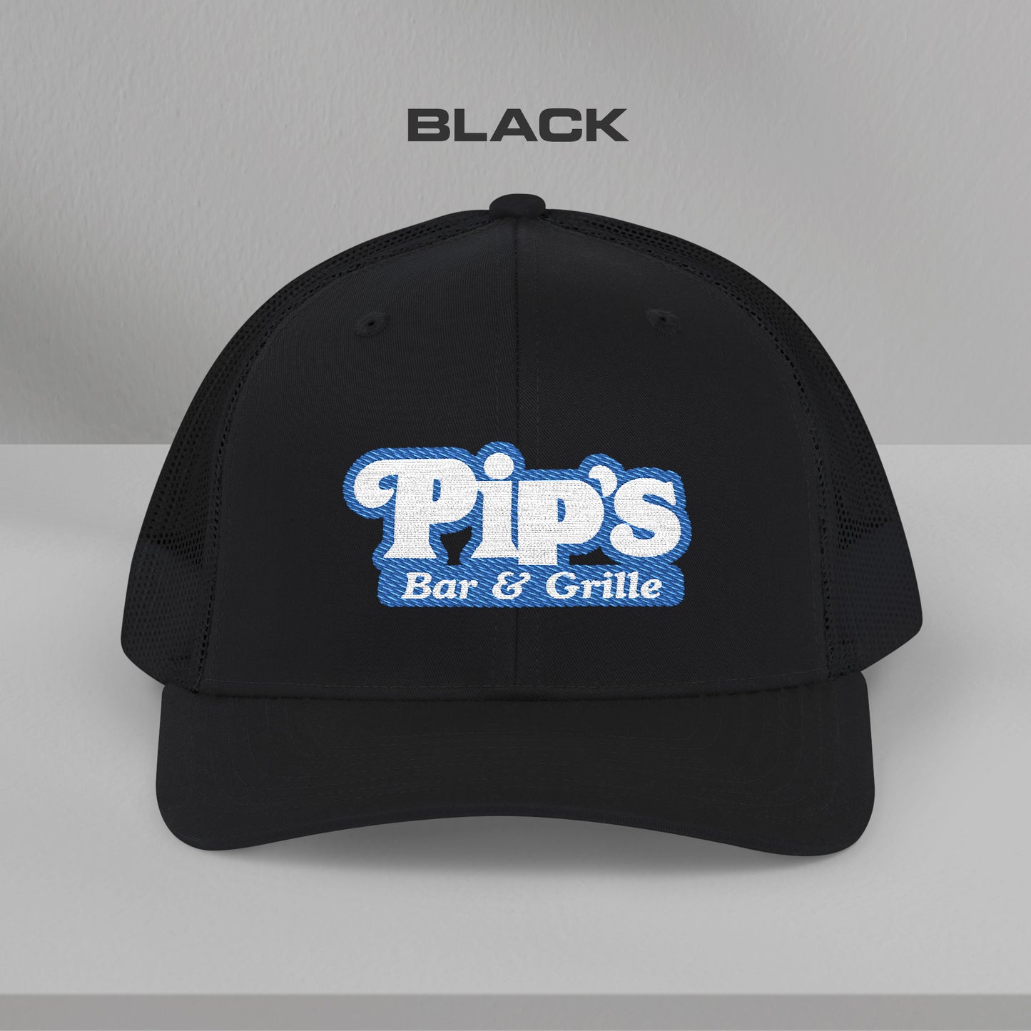Front view of black Richardson 112 trucker hat with embroidered Pip’s Bar & Grille logo inspired by Severance.