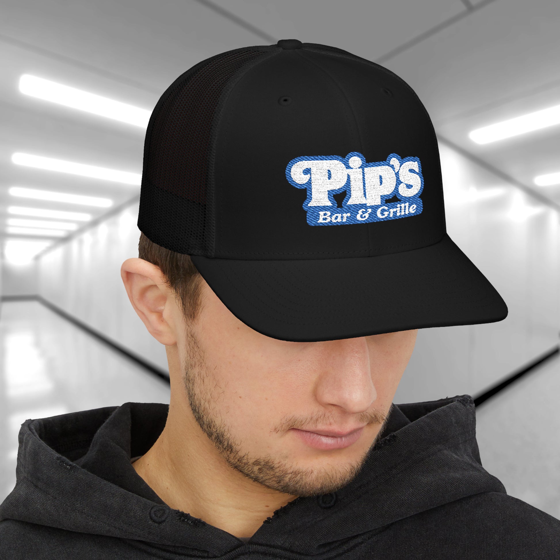 Man wearing black Richardson 112 trucker hat with embroidered Pip’s Bar & Grille logo inspired by Severance.